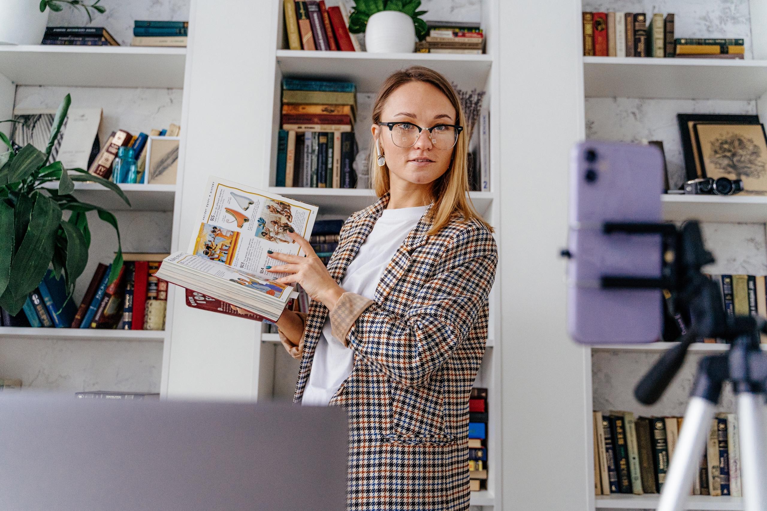 profesora dando clases en linea con un libro