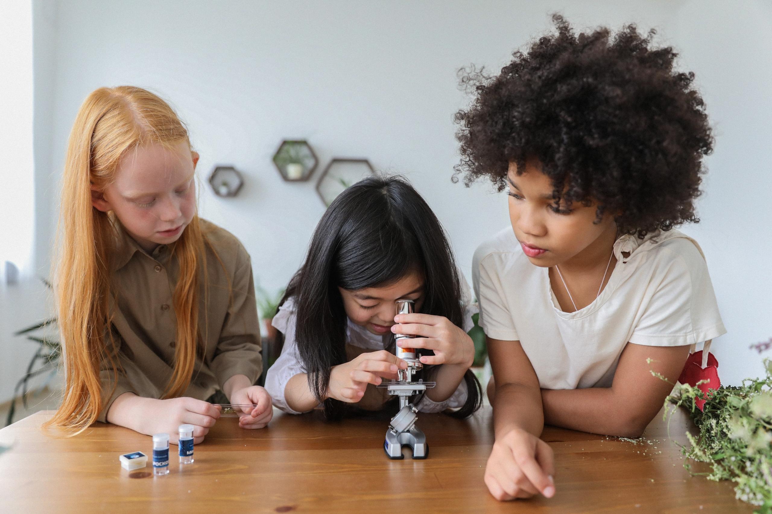 tres niñas viendo a través de un microscopio
