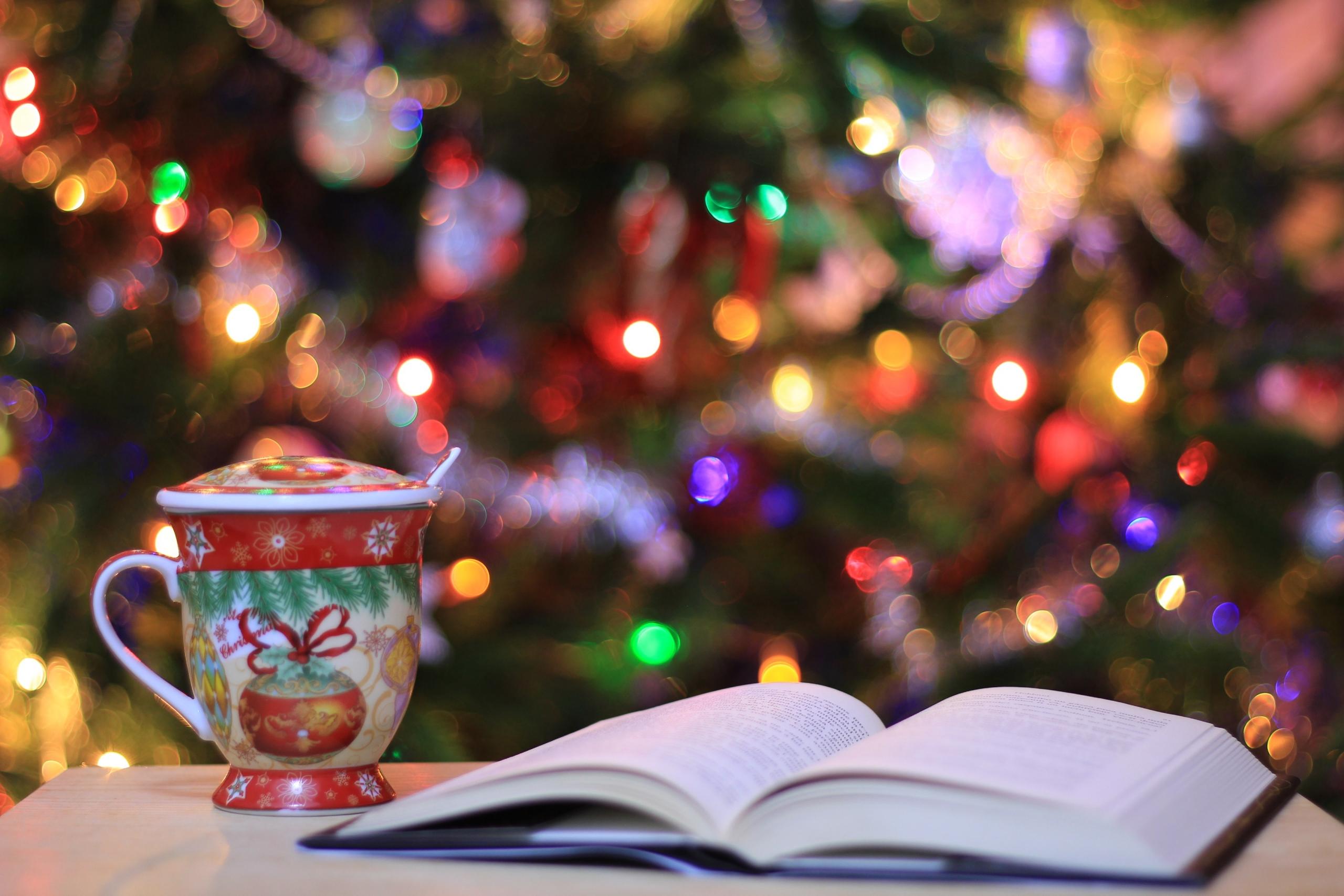 libro con tasa y árbol de navidad de fondo