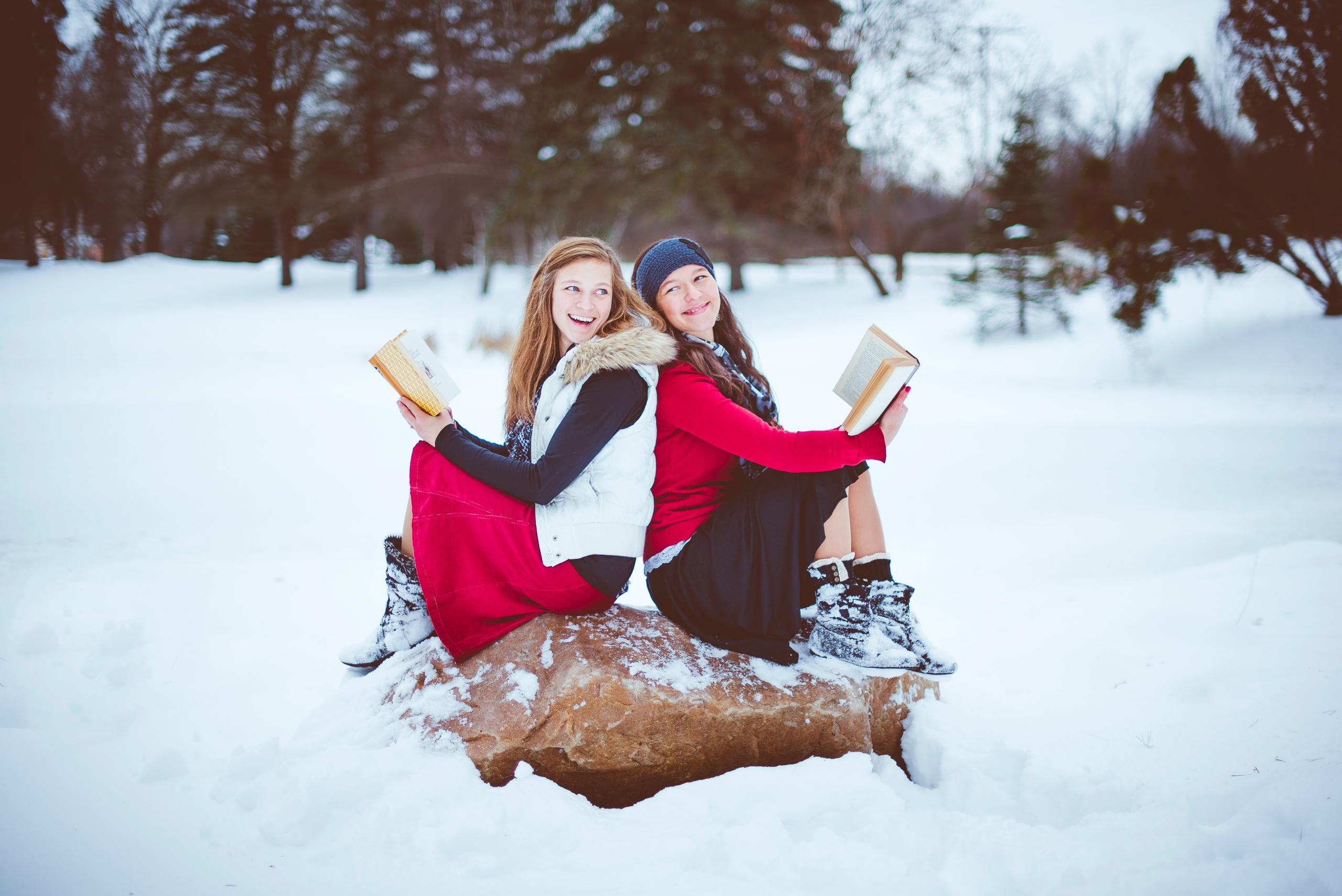 dos chicas leyendo libros en medio de la nieve