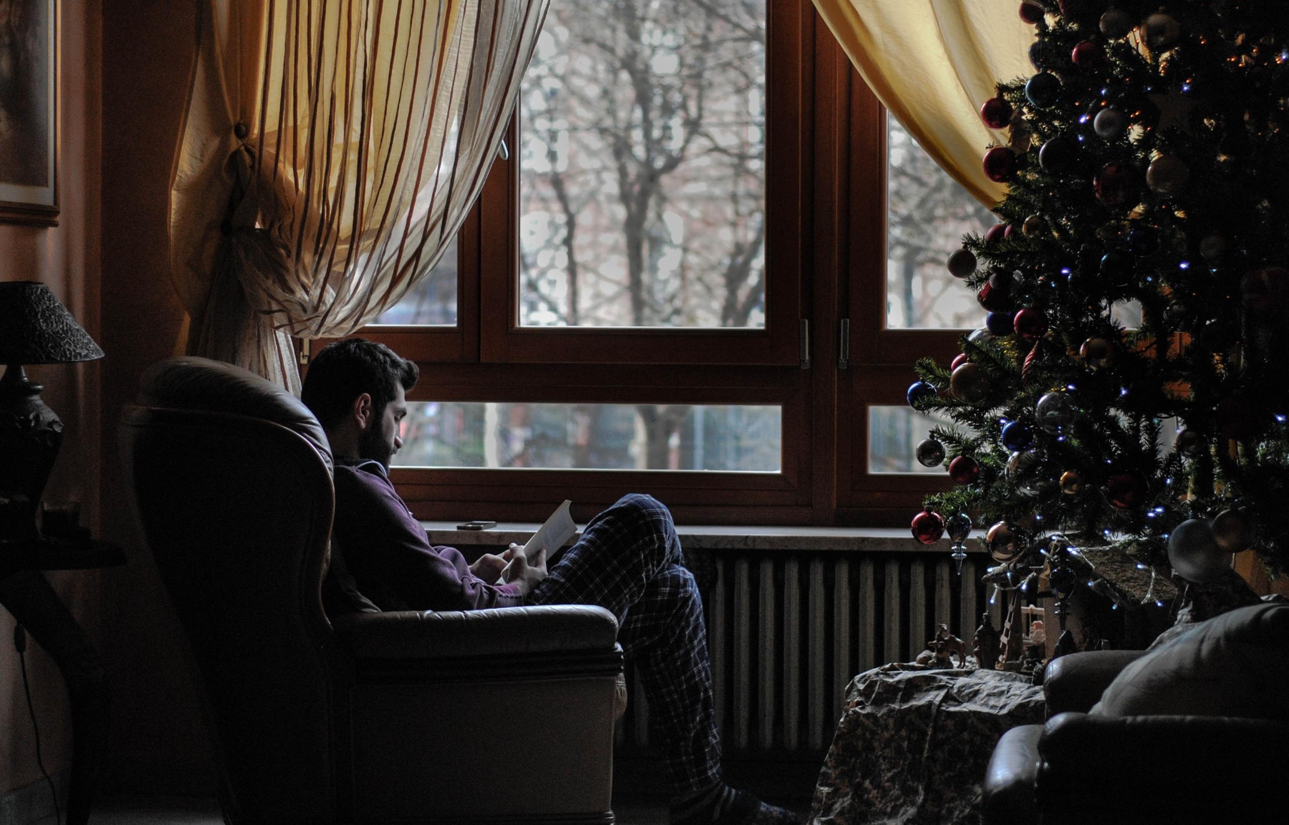 persona sentada leyendo un libro frente a una ventana