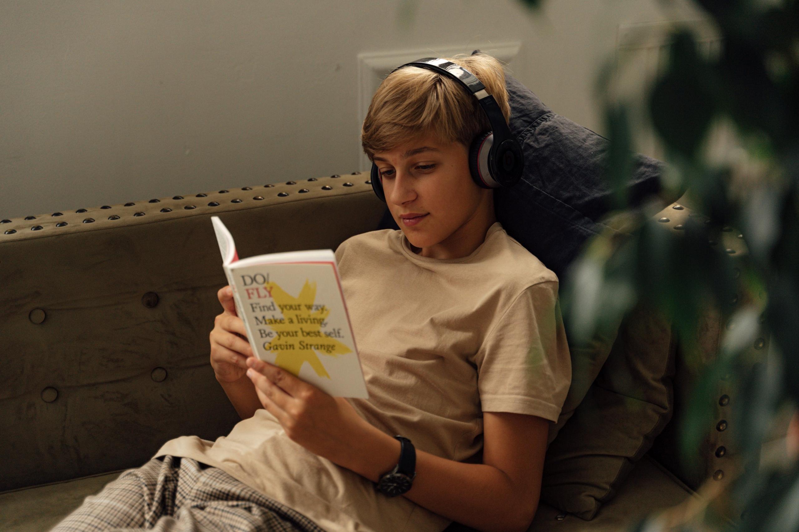 joven leyendo un libro con auriculares