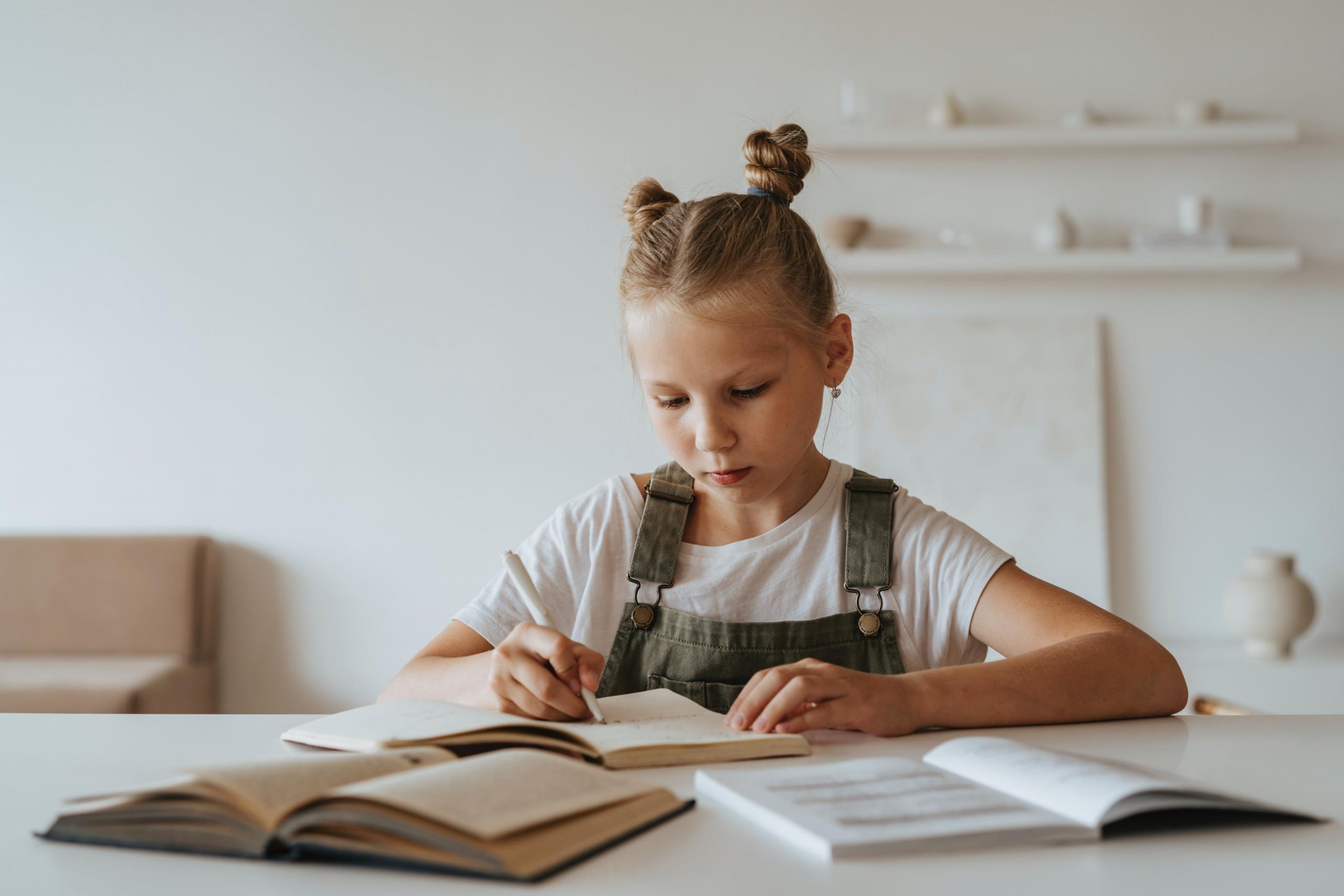chica haciendo la tarea con libros en frente