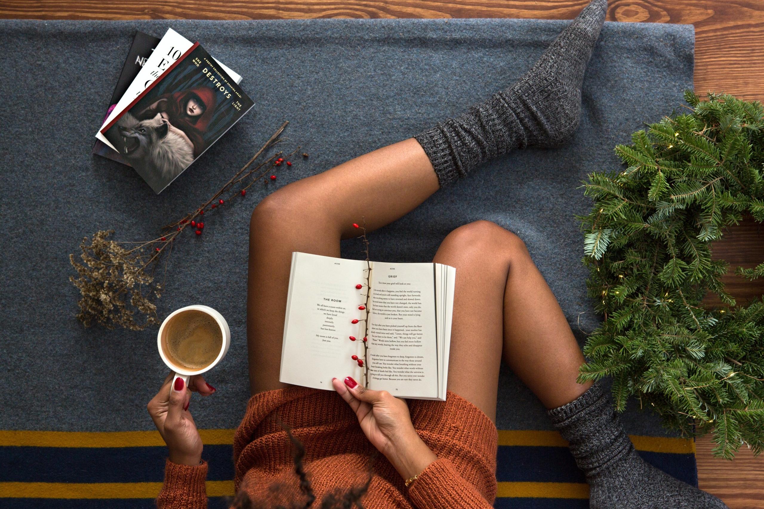 persona leyendo libros en navidad con una taza en la mano