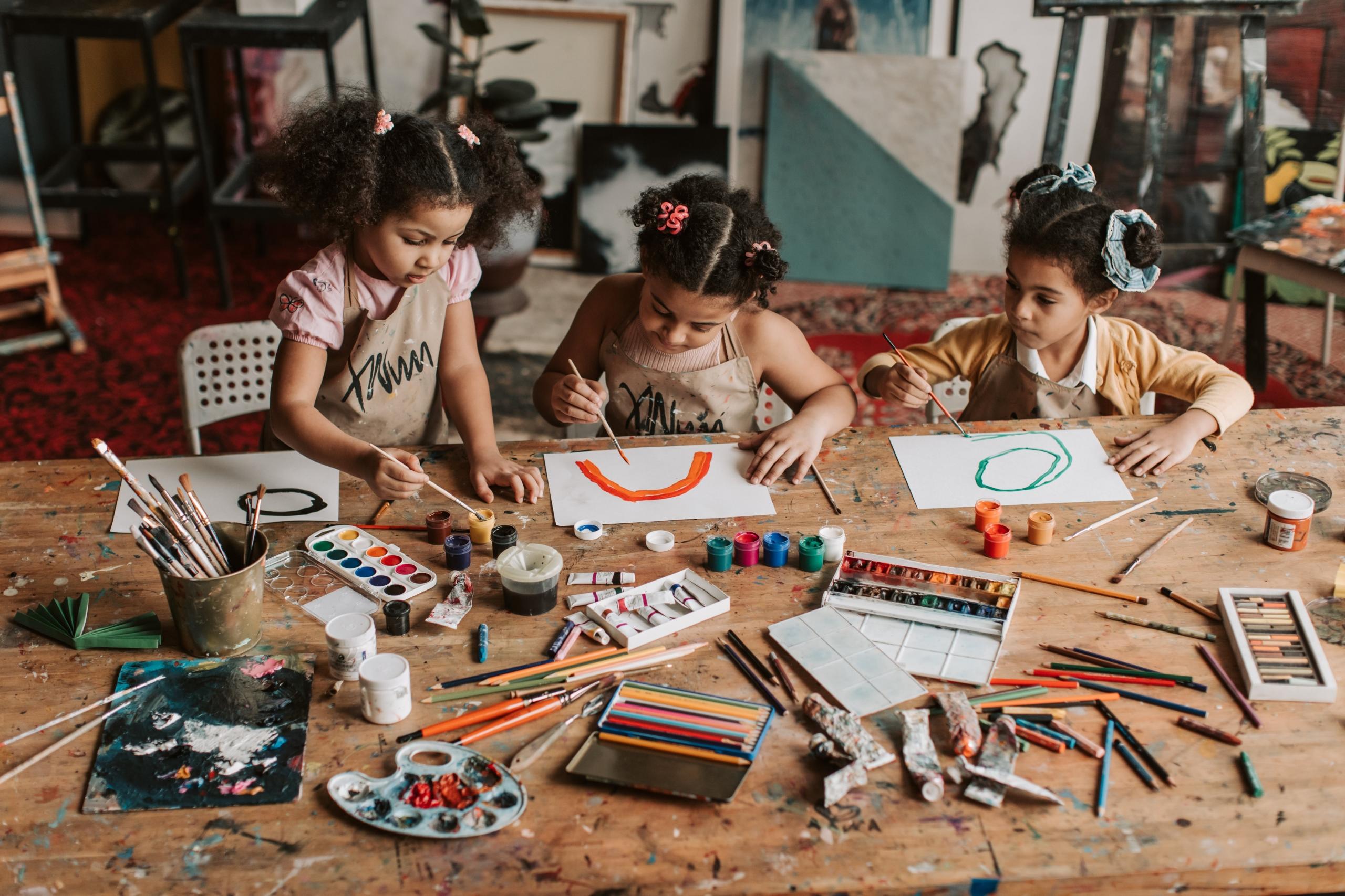 niñas dibujando en una mesa con muchos colores