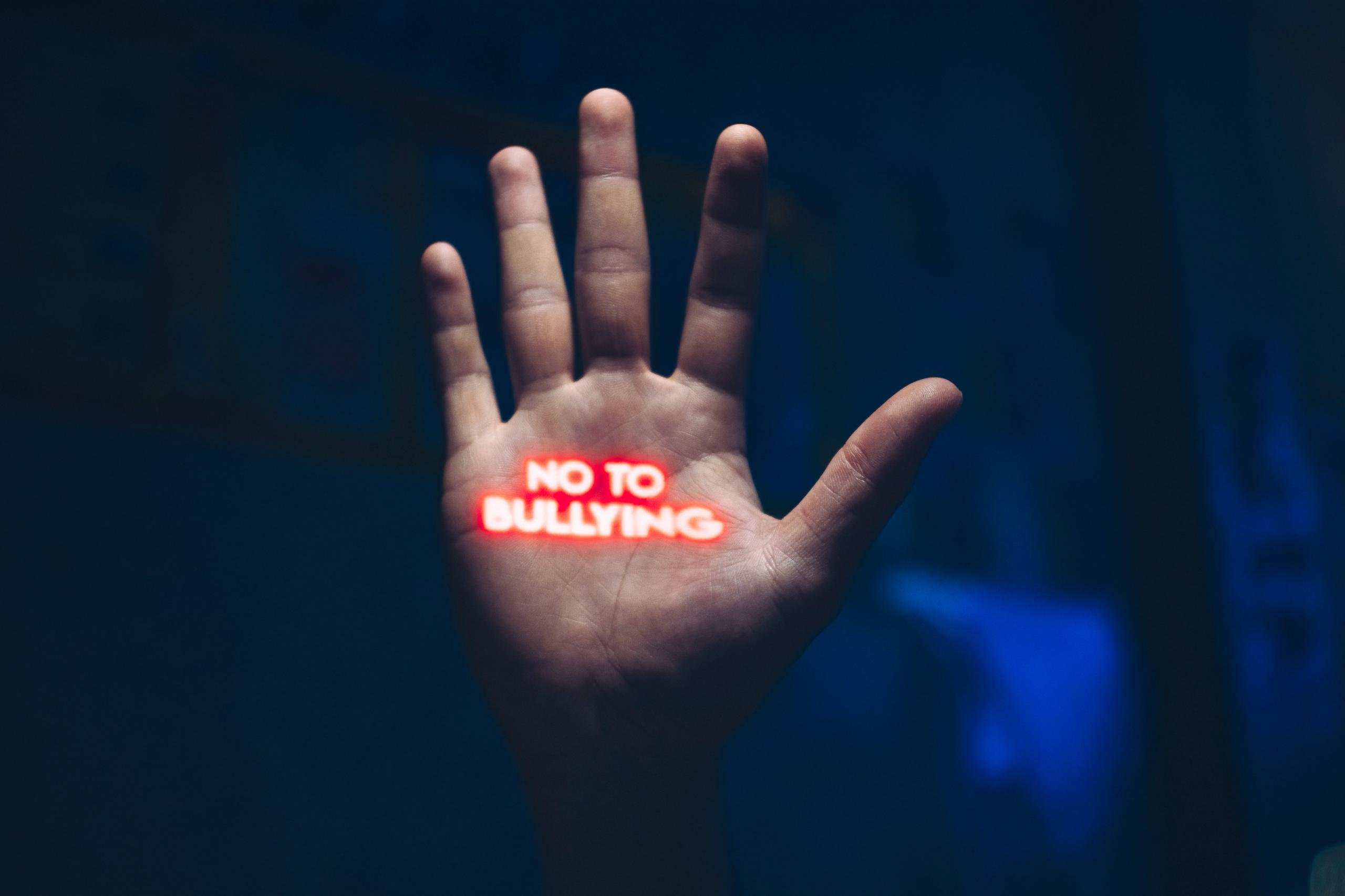 mano con una proyección de la frase "no al bullying"