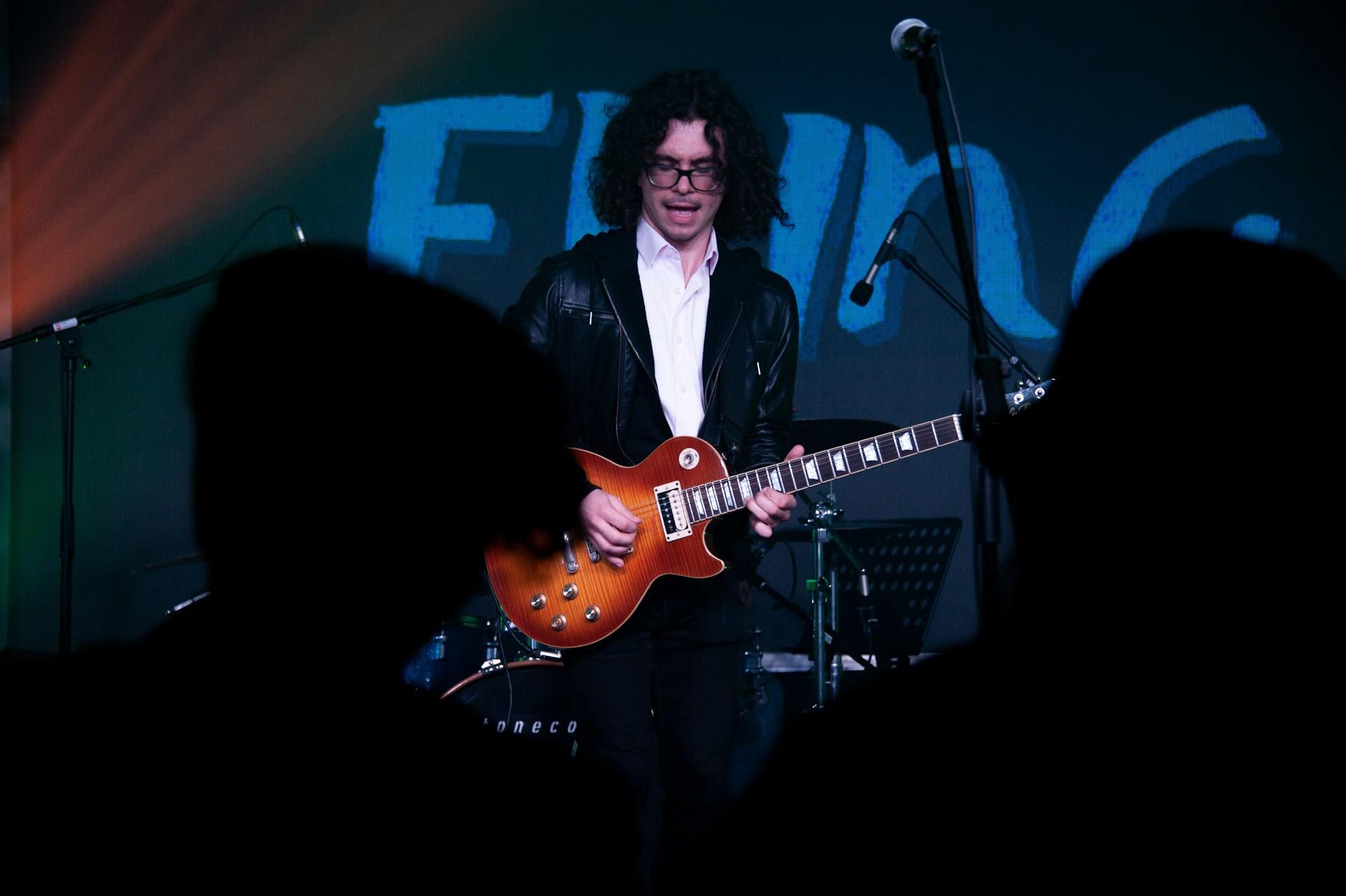 Persona en escenario cantando y tocando la guitarra