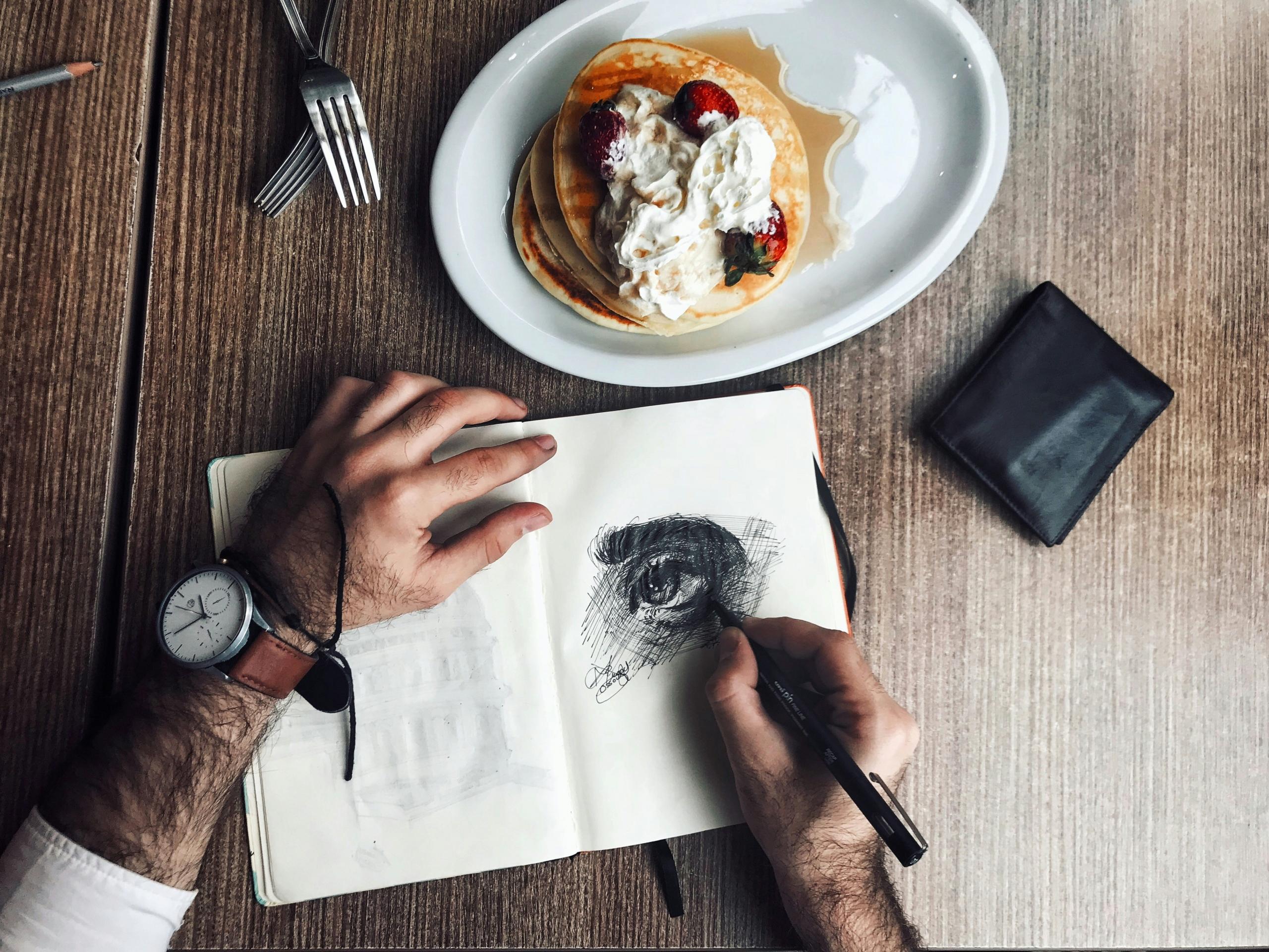 persona dibujando un ojo en un cafe