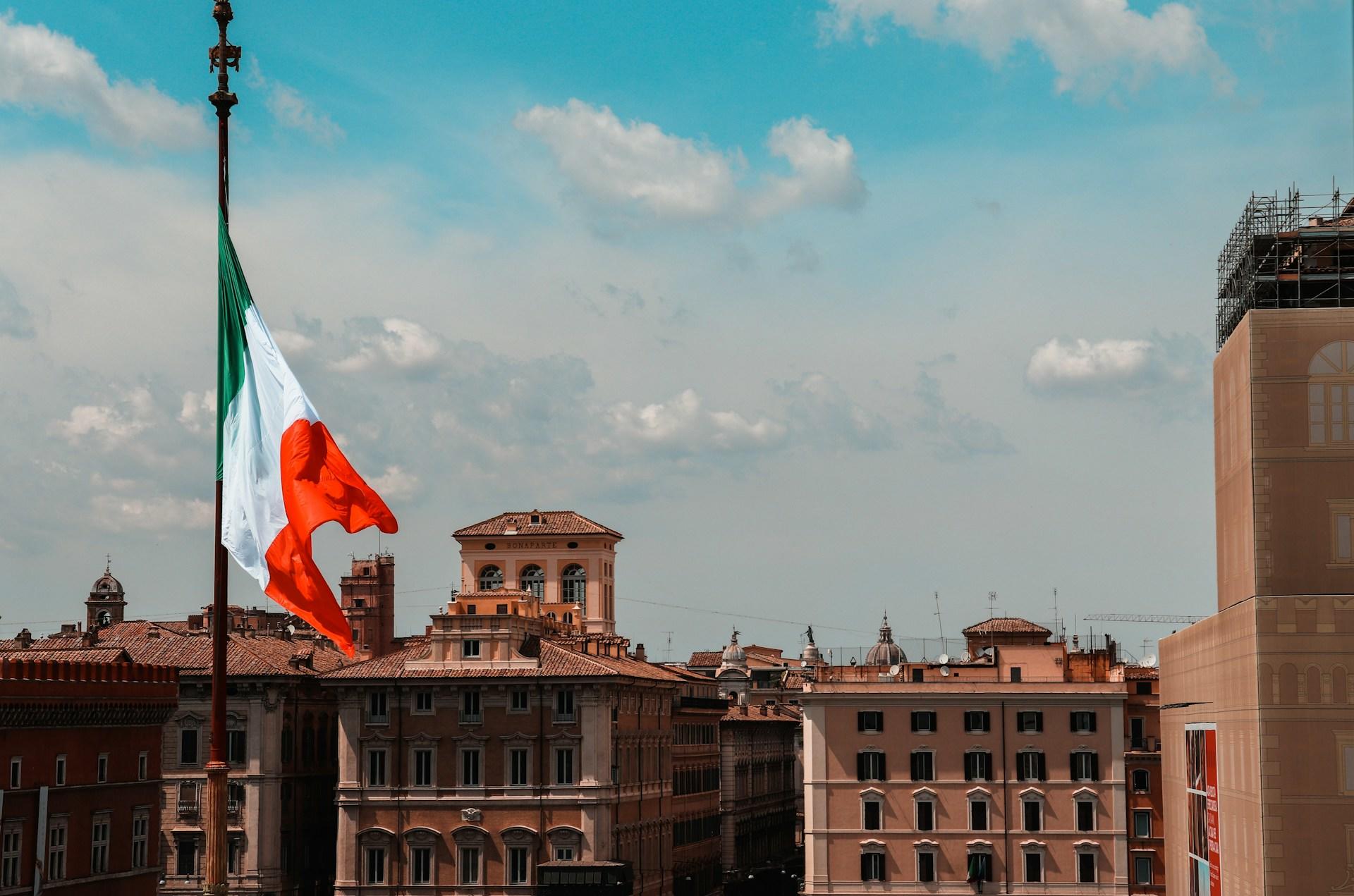 bandera italiana con ciudad italiana de fondo