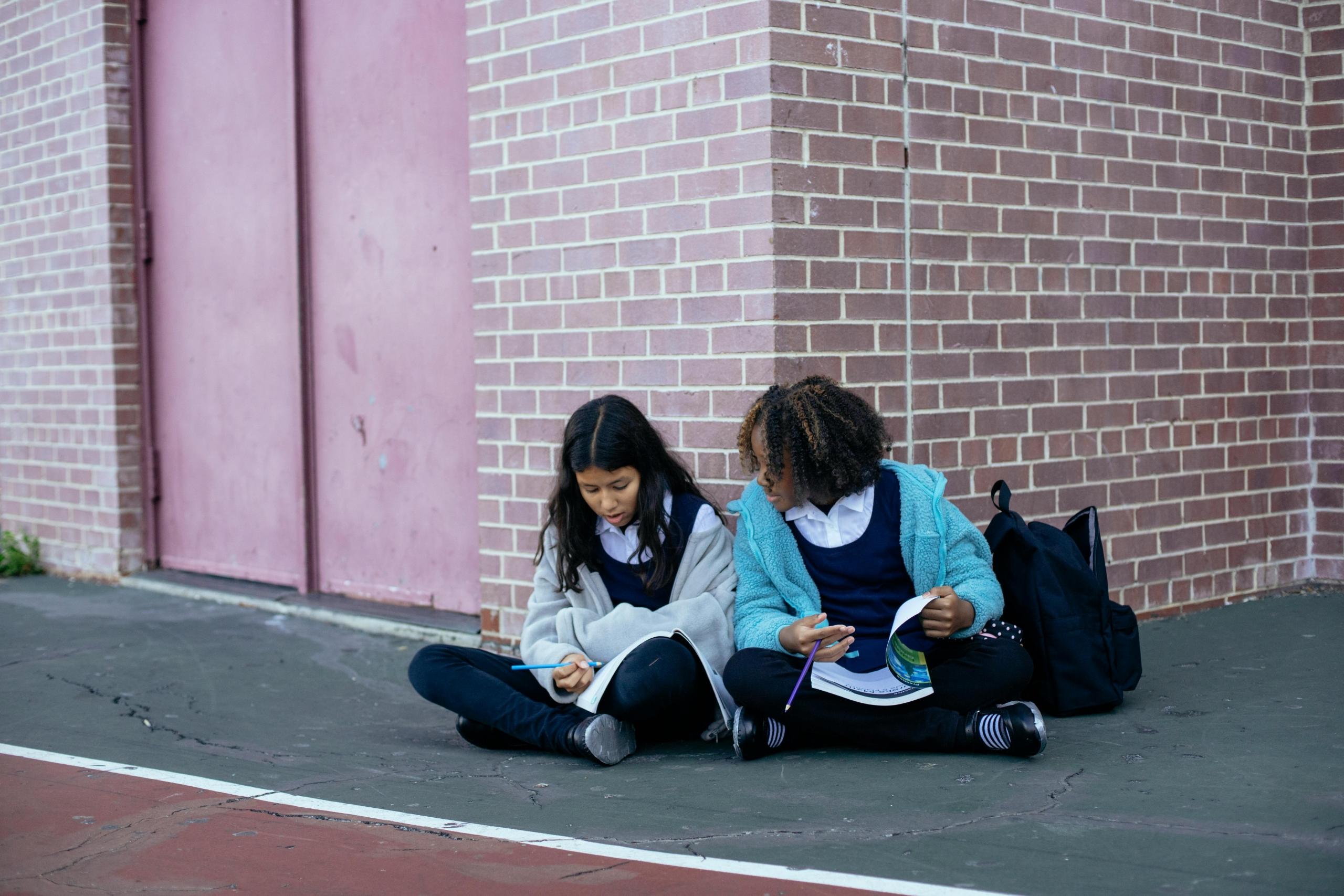 dos chicas sentadas con sus libros de texto