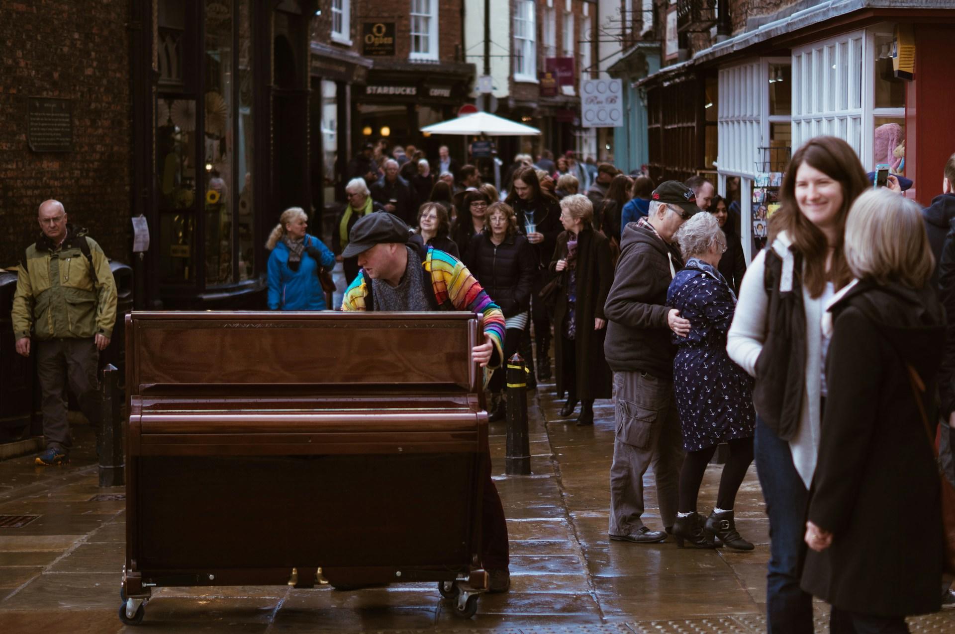 persona con un piano en medio de multitud