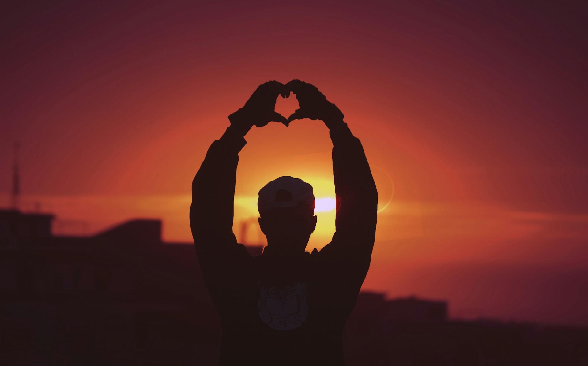 persona haciendo un corazón al aire