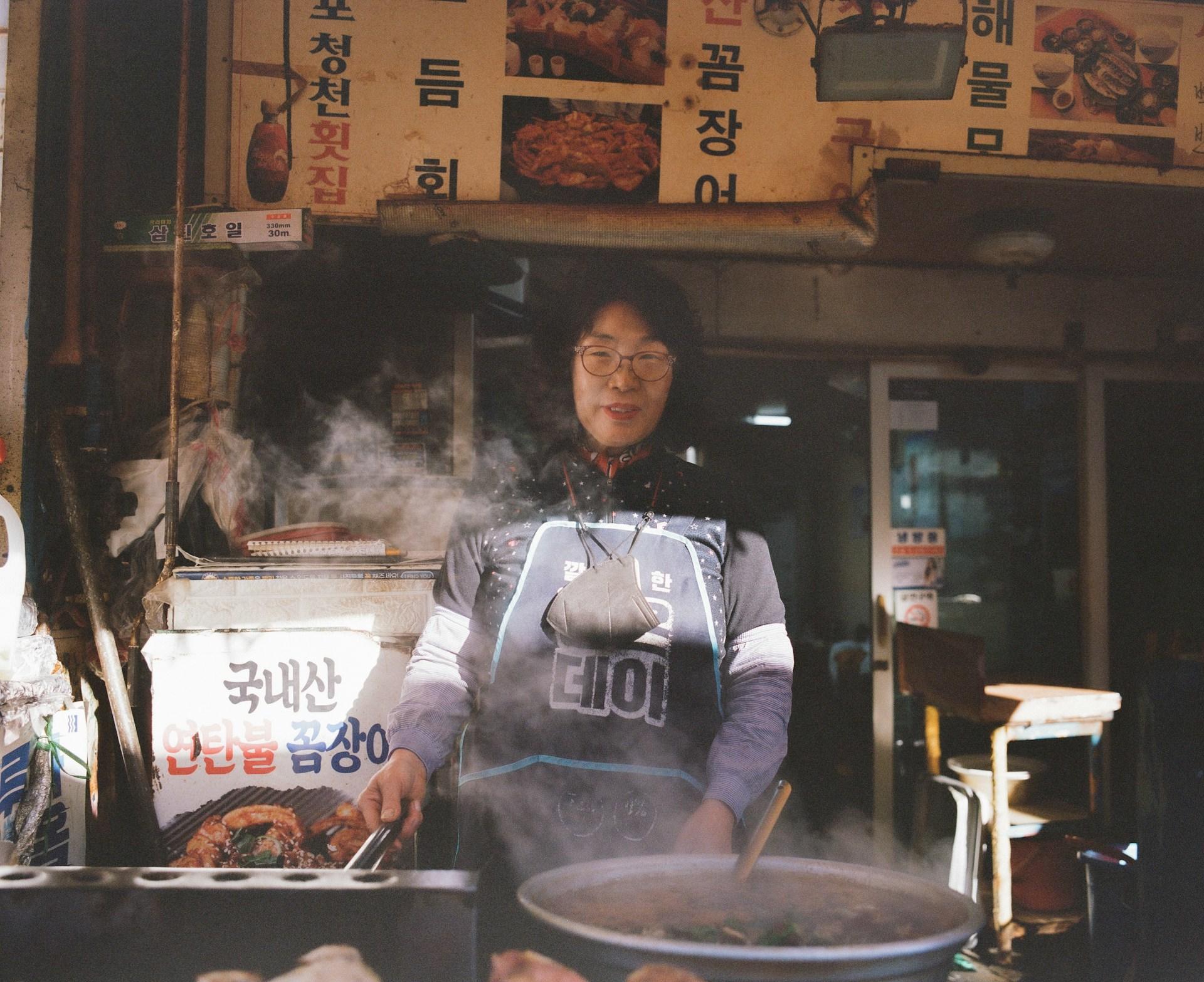 mujer cocinando en un stand callejero corea