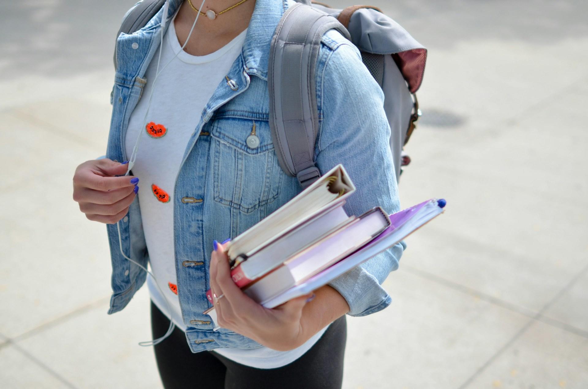 chica caminando con libros en la mano