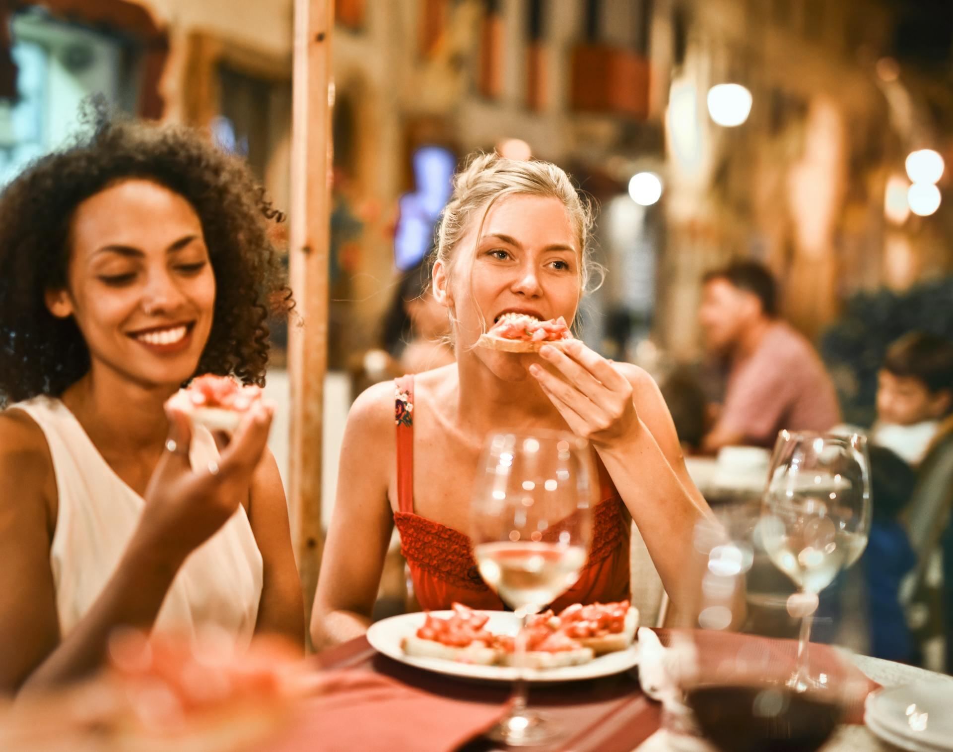 Dos mujeres comiendo pizza.