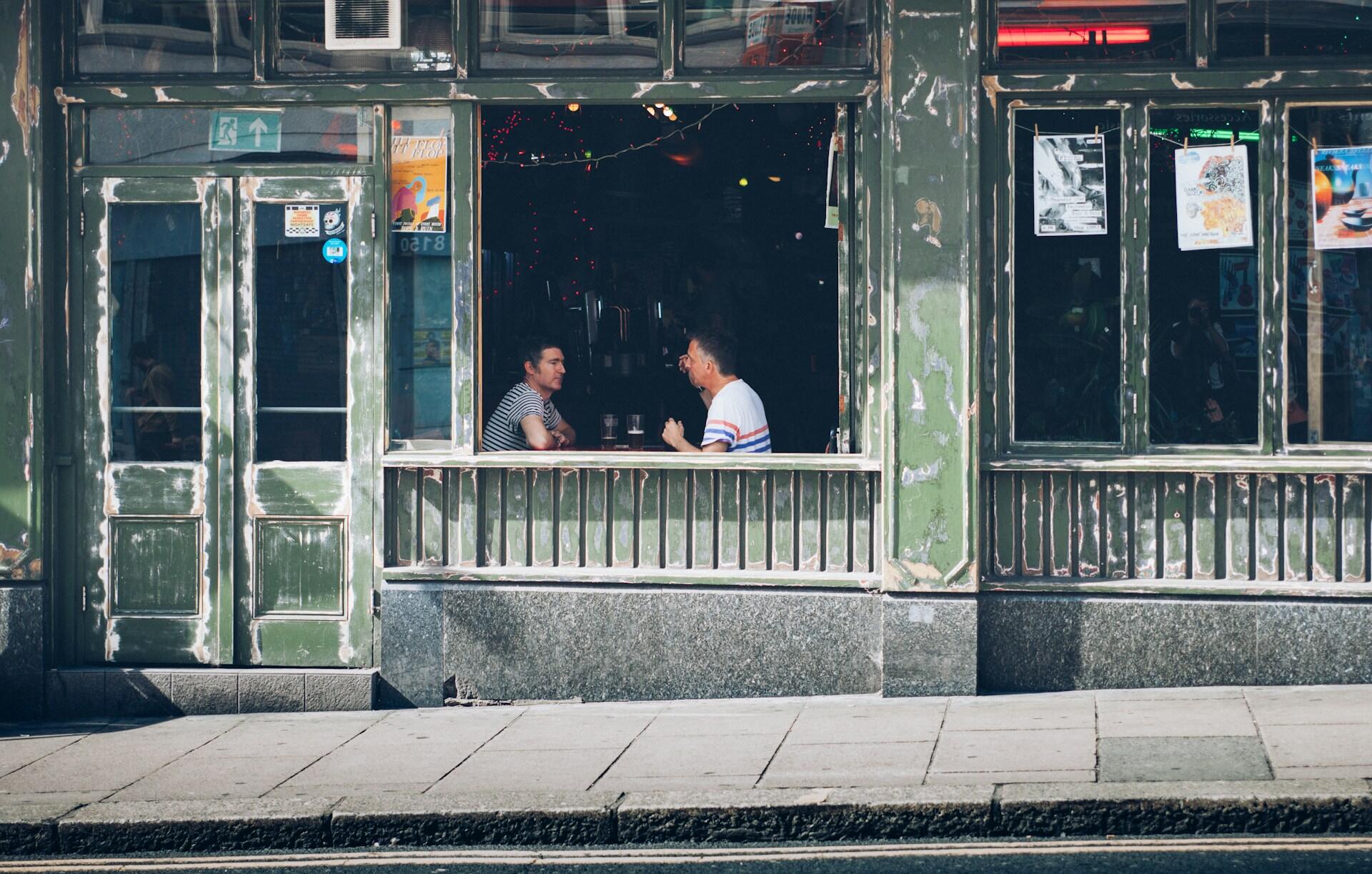 Dos hombres conversando dentro del edificio verde.