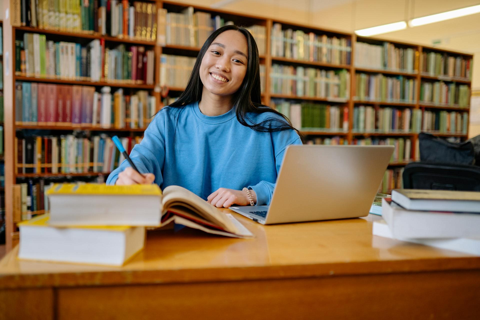Mujer con buzo azul sentada en la mesa de la biblioteca .