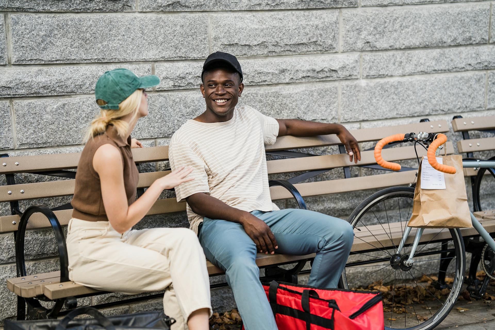 Un hombre y una mujer conversando en el banco al lado de una bicicleta.