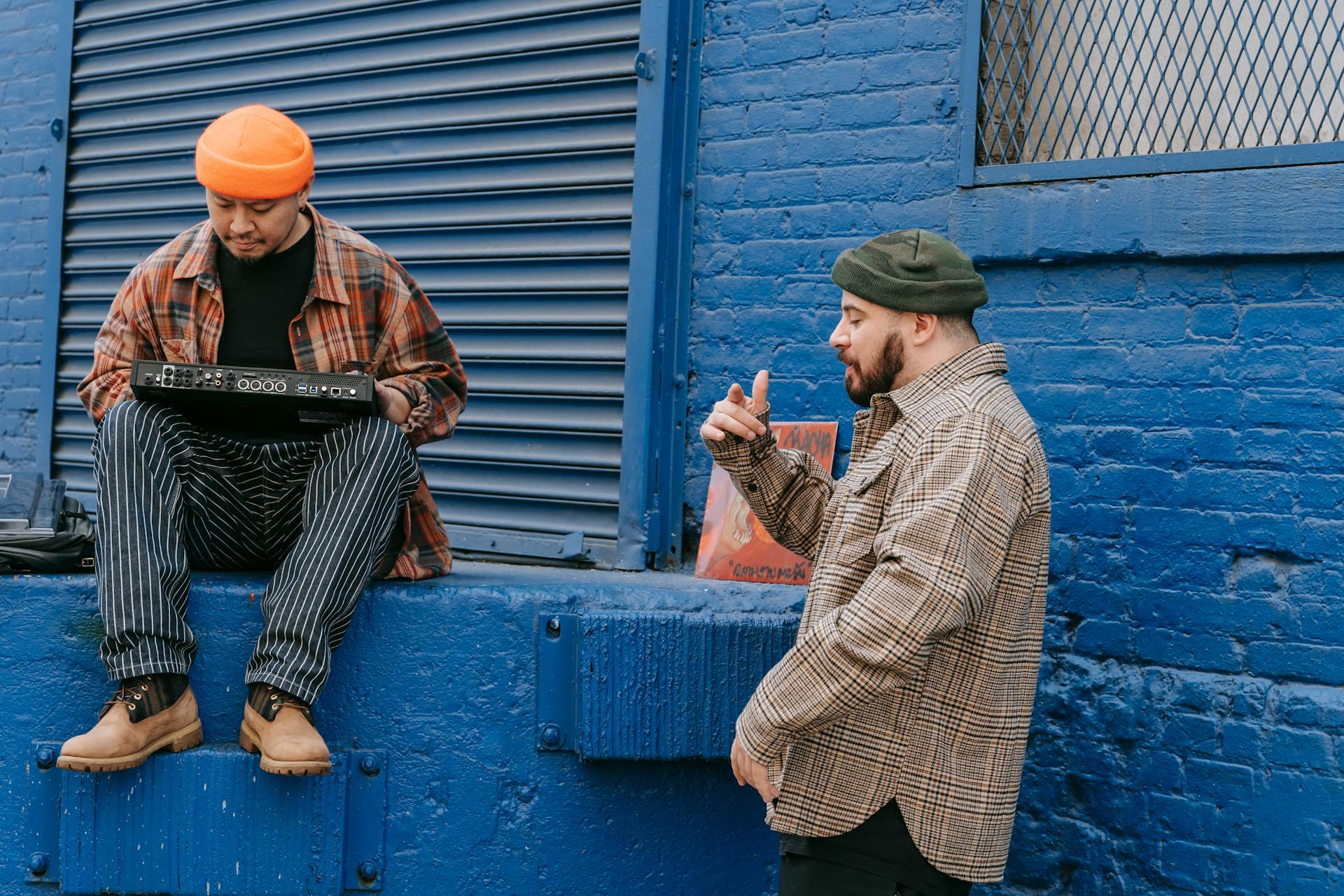 dos hombres improvisando en música con camisas a cuadros sobre una pared azul