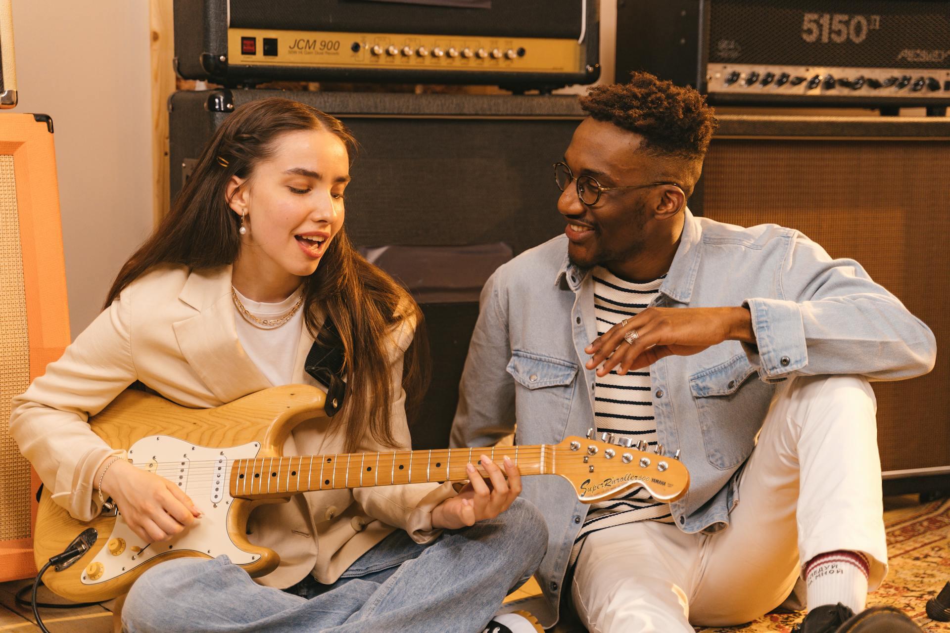 Mujer con guitarra eléctrica aprende a cantar junto a un hombre con lentes