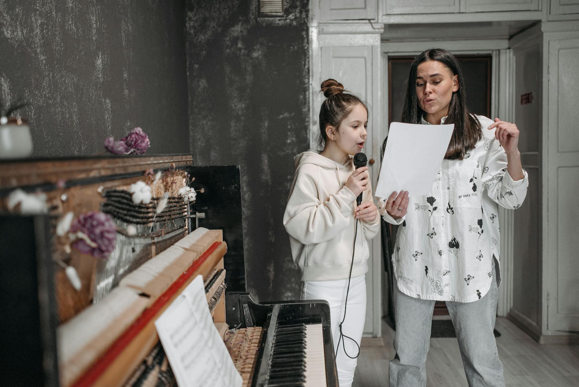 Mujer y niña cantando junto a un piano