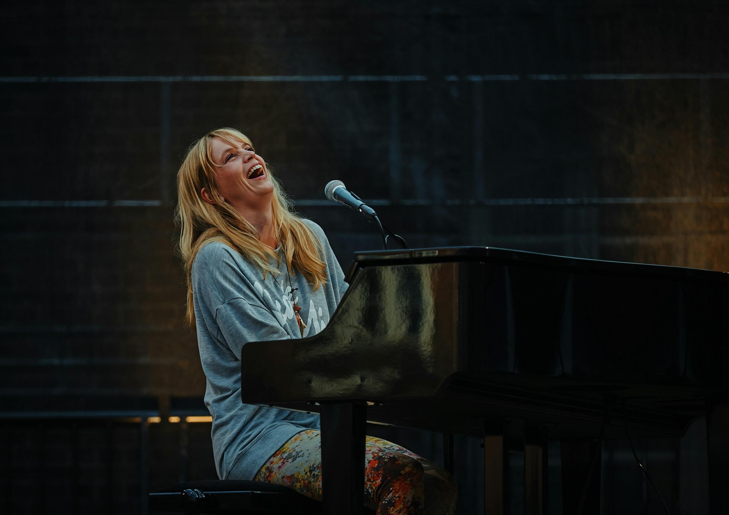 mujer rubia sentada tocando piano