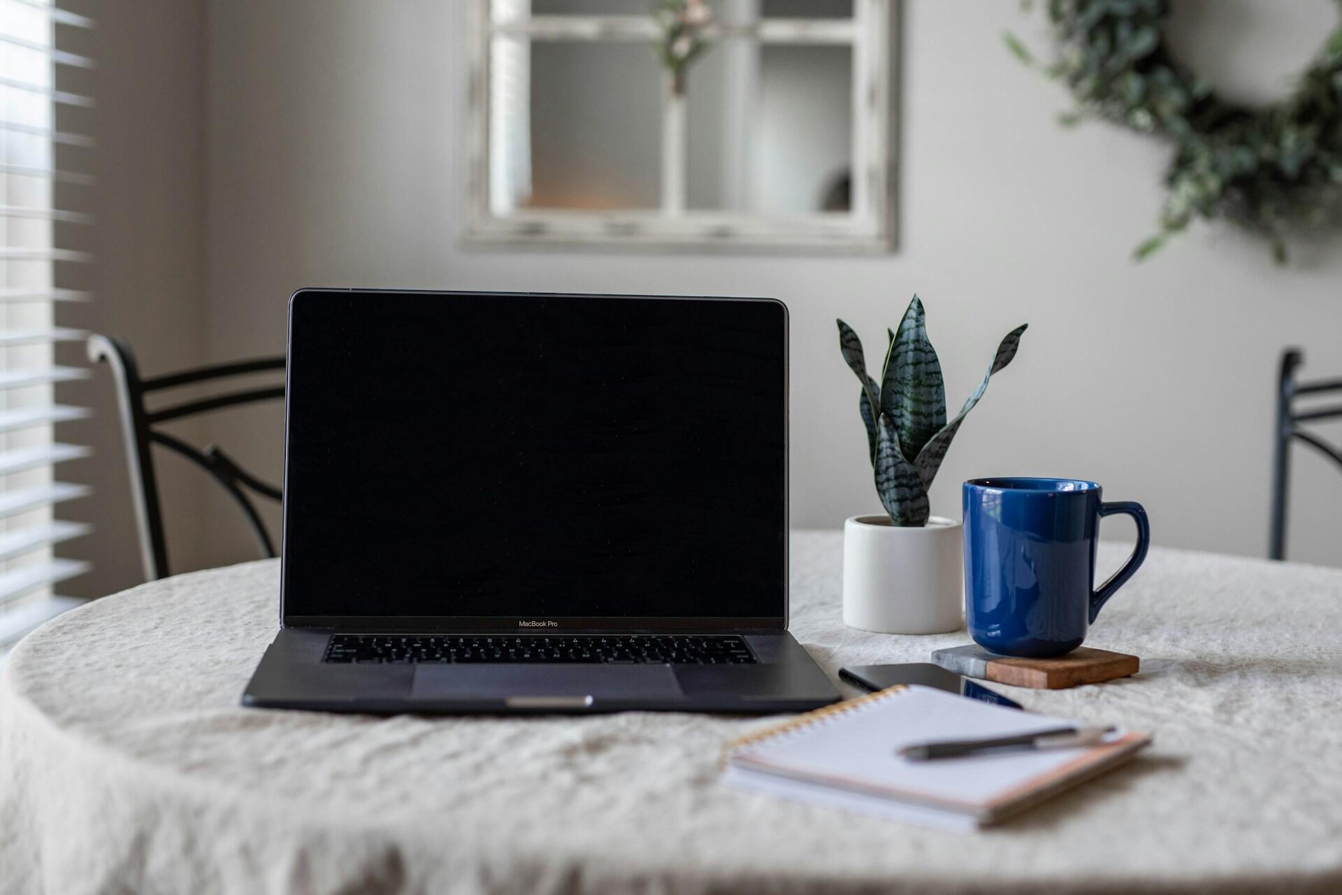 computadora con libreta mas taza de café al lado 