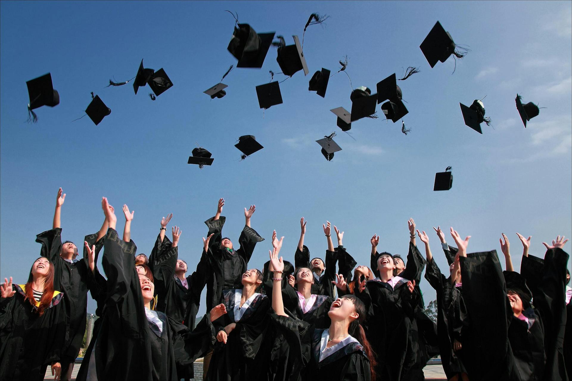 Grupo de egresados tirando sombreros de graduación al cielo en modo de festejo