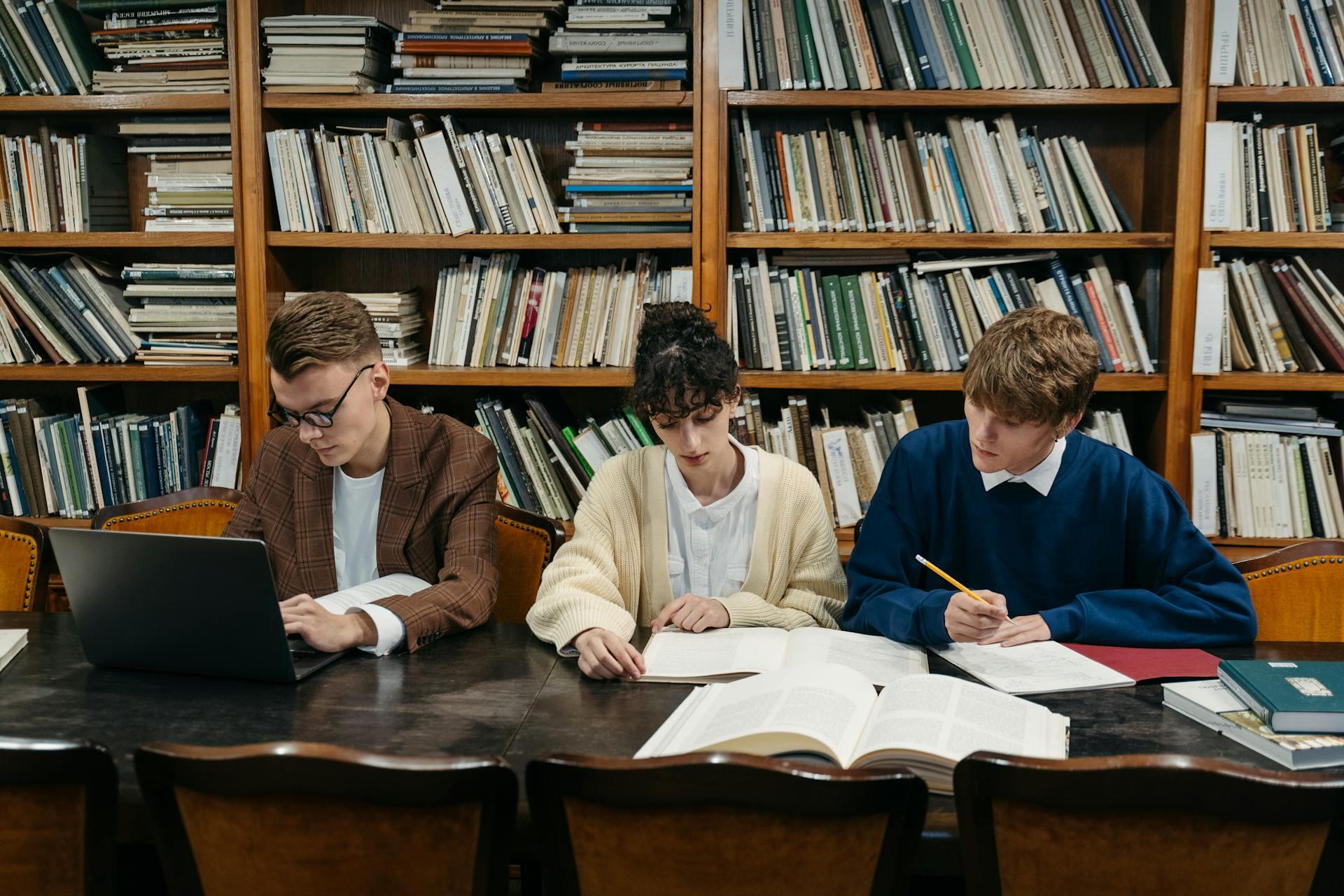 dos hombres y una mujer estudiando sentados en una mesa
