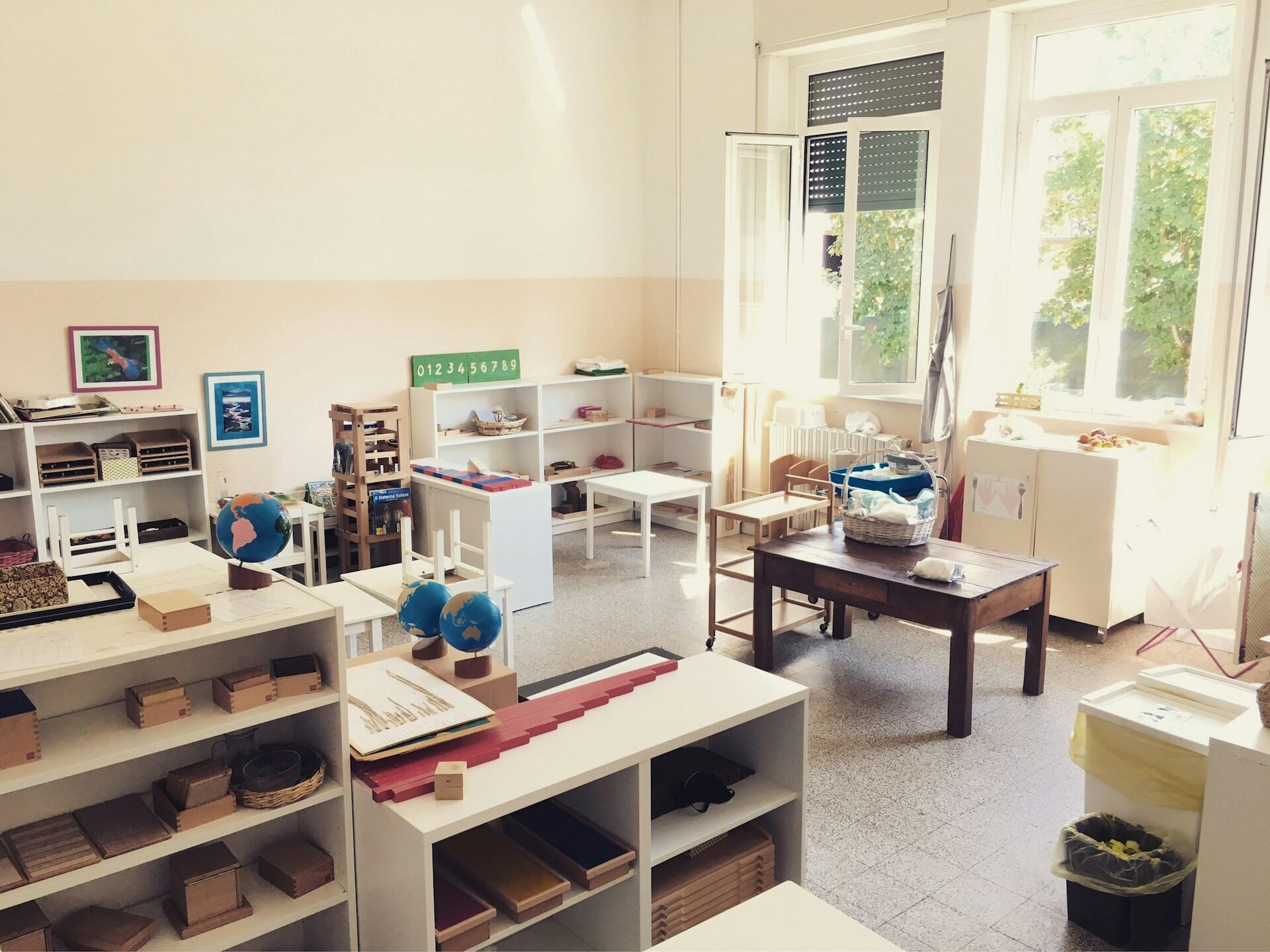 Aula en Somma, Italia, que muestra un entorno preparado Montessori con estanterías bajas y materiales didácticos de madera. Foto de Iwan Buetti.