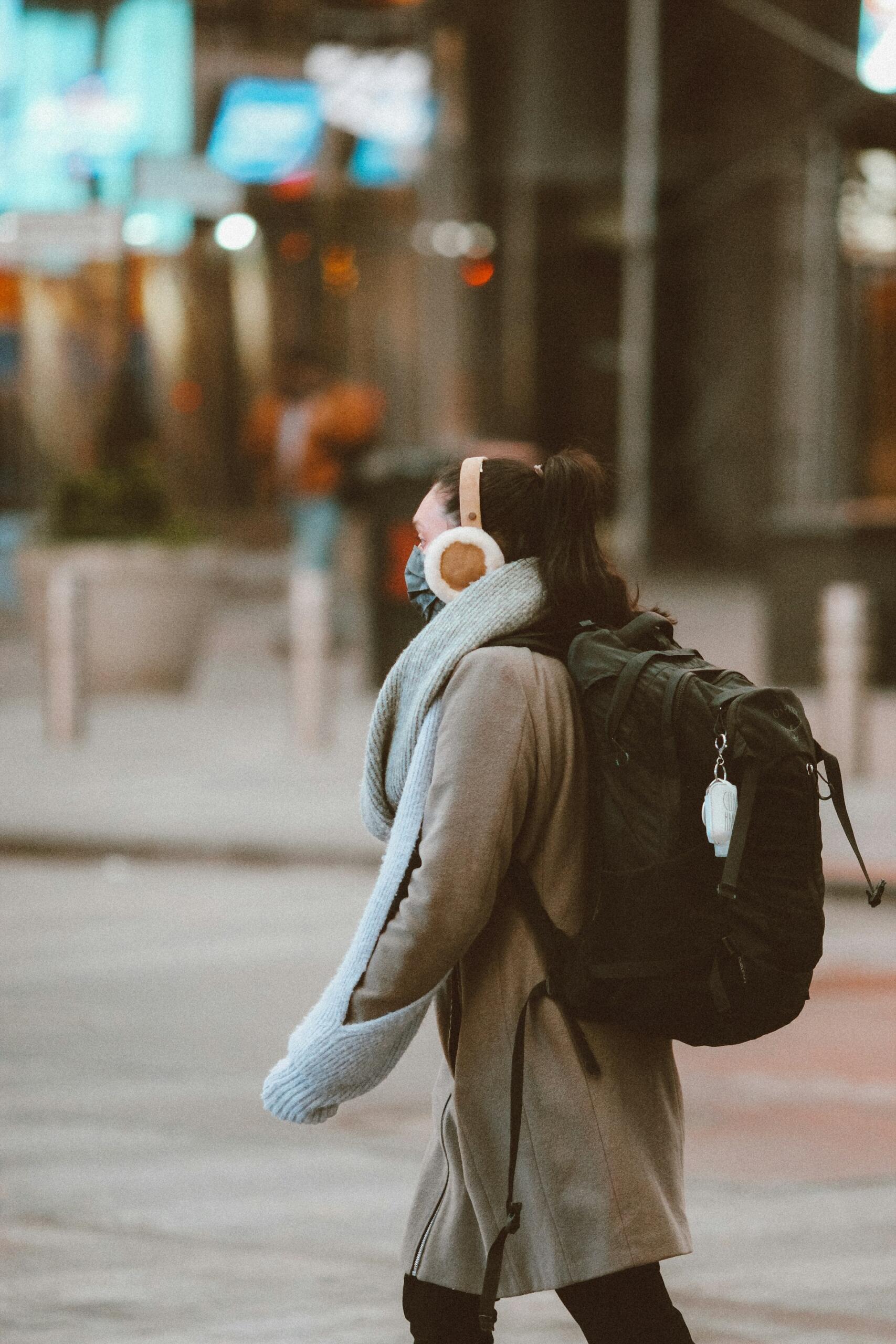 Mujer caminando en invierno por la ciudad, mientras escucha un podcast con sus headphones para aprender alemán. Fuente: Jon Tyson