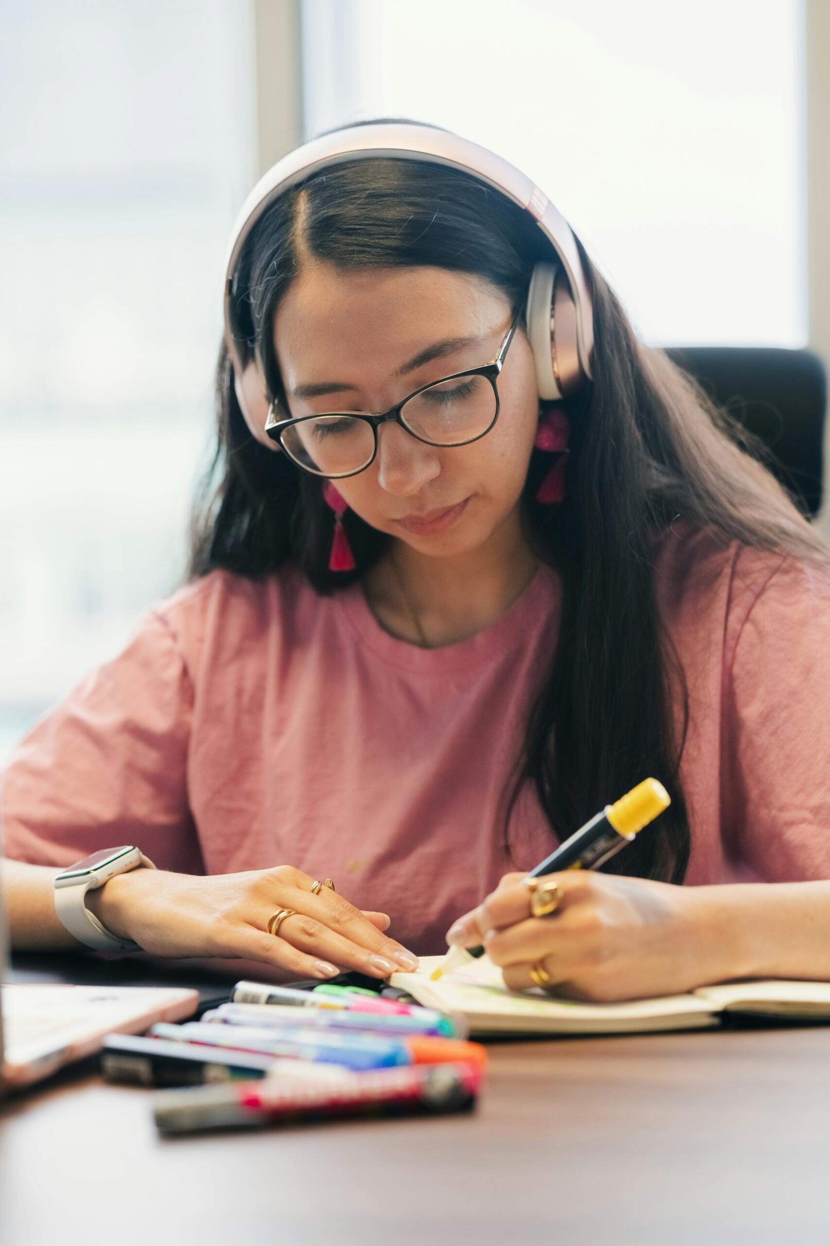 Foto de Julio Lopez en Unsplash. Una mujer joven estudiando con auriculares, una forma efectiva de practicar un nuevo idioma.