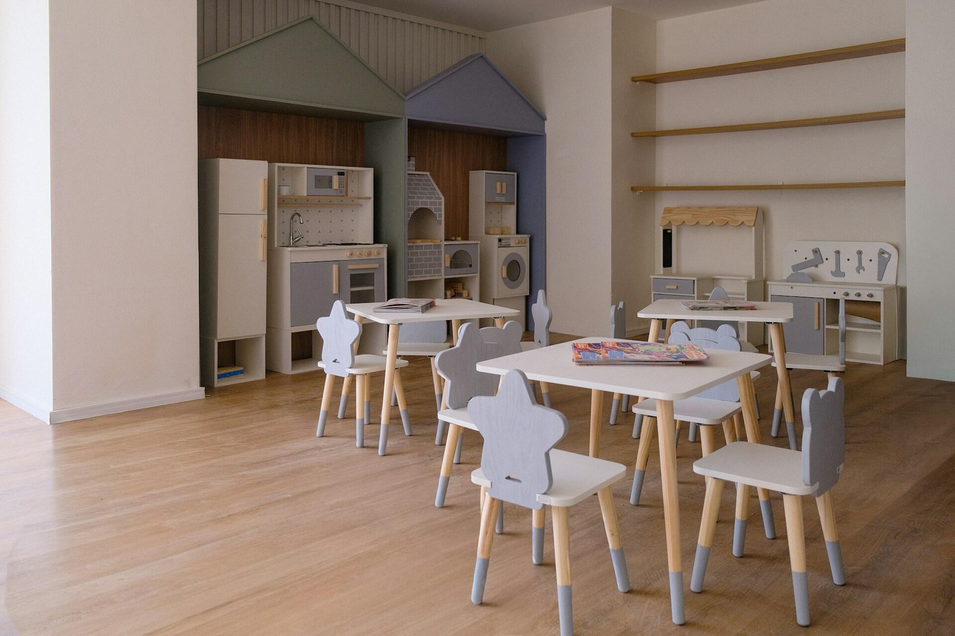 Imagen de Unsplash de un aula infantil Montessori vacía con mesas, sillas pequeñas y mobiliario de madera al fondo. Foto de Camila Mofsovich.