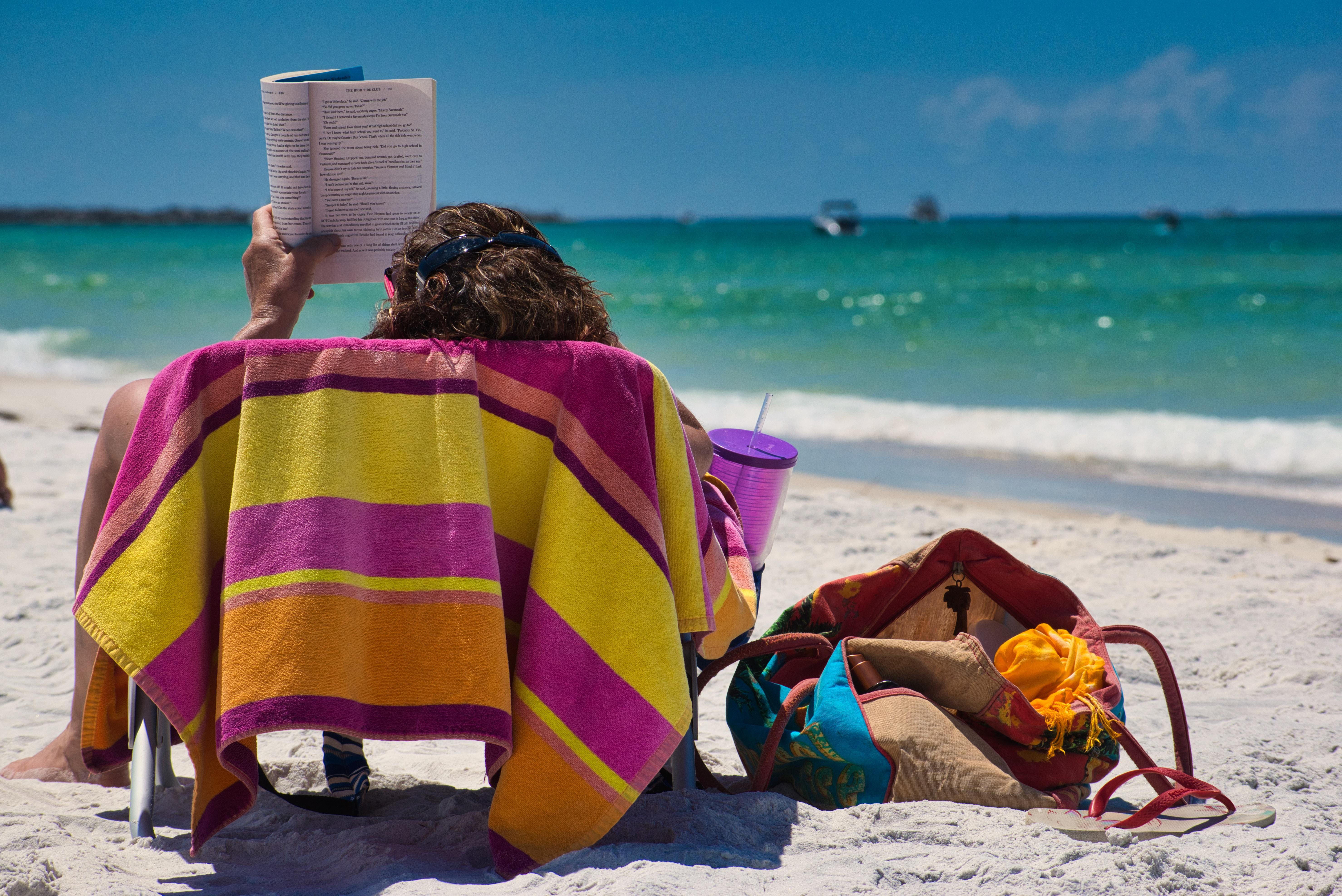 woman reading book on beach