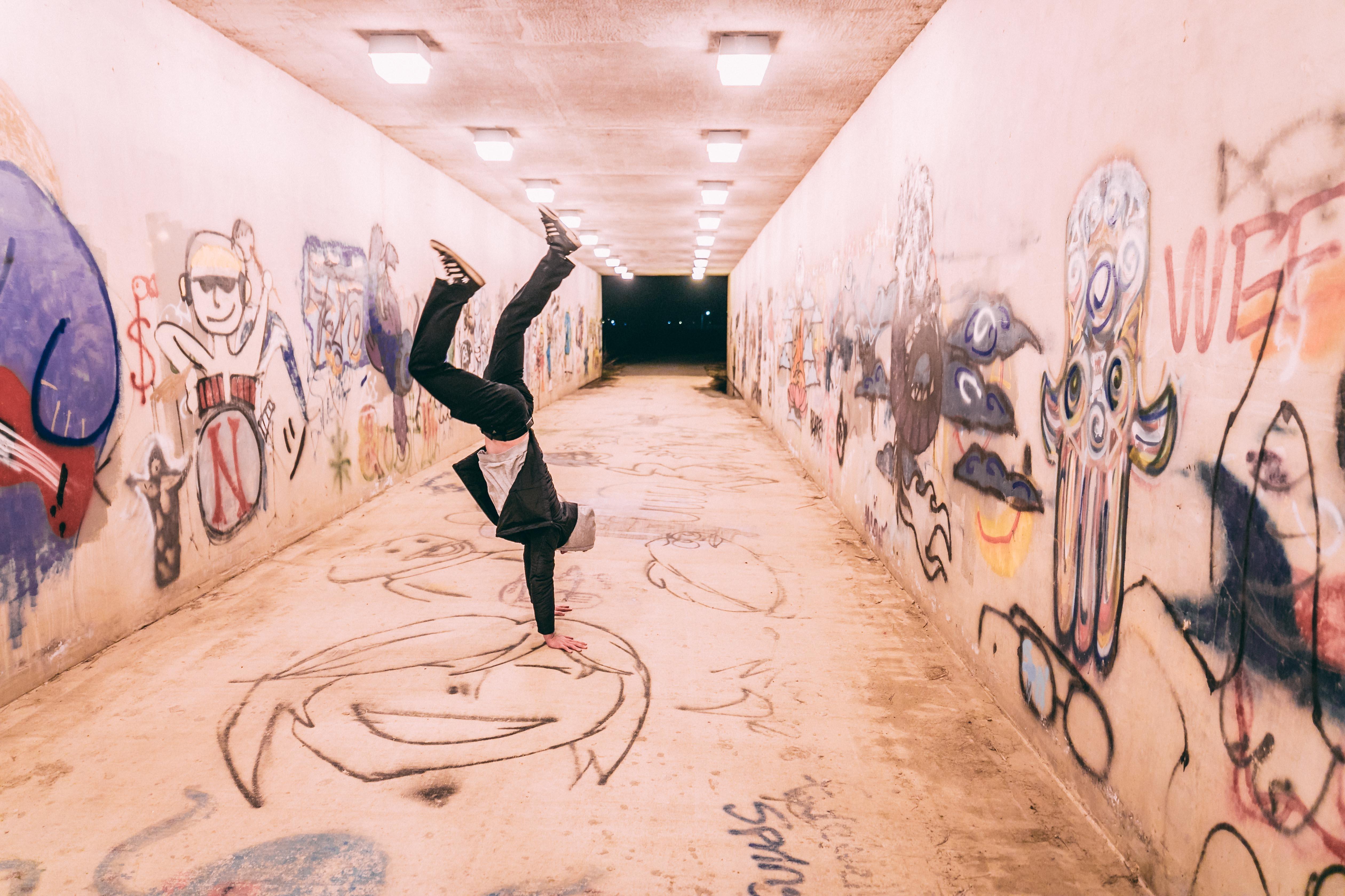 guy breakdancing in tunnel with graffiti