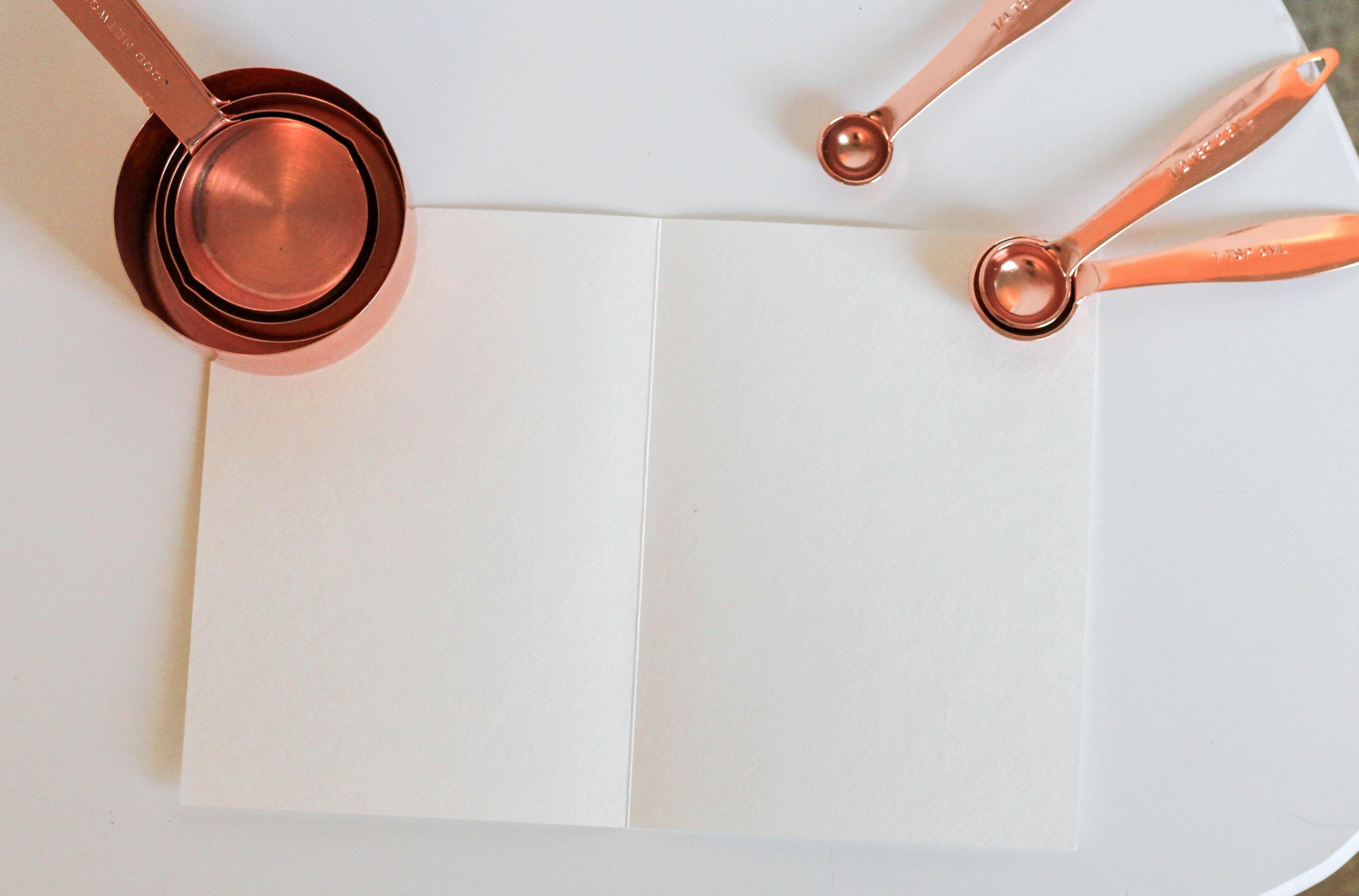 copper measuring spoons and measuring cups and notebook