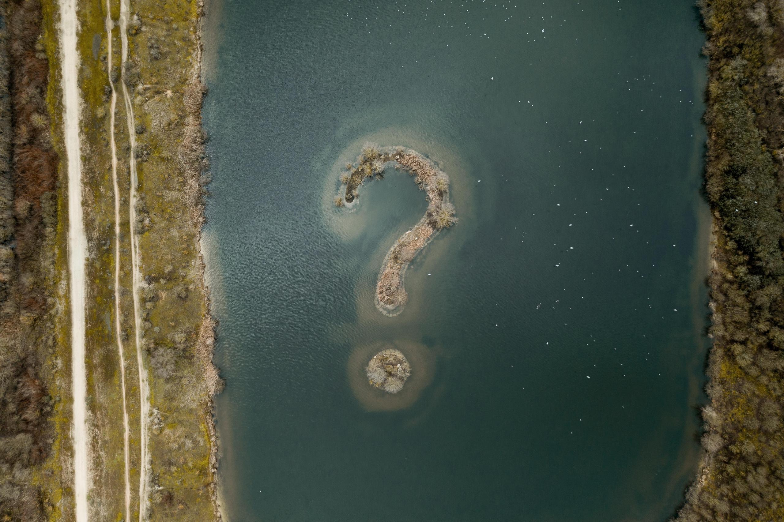 aerial view of question mark shaped island in lake