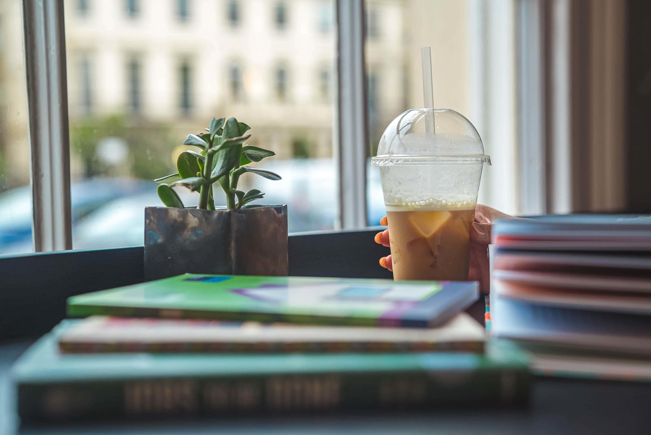 person reading books and drinking iced coffee in cafe