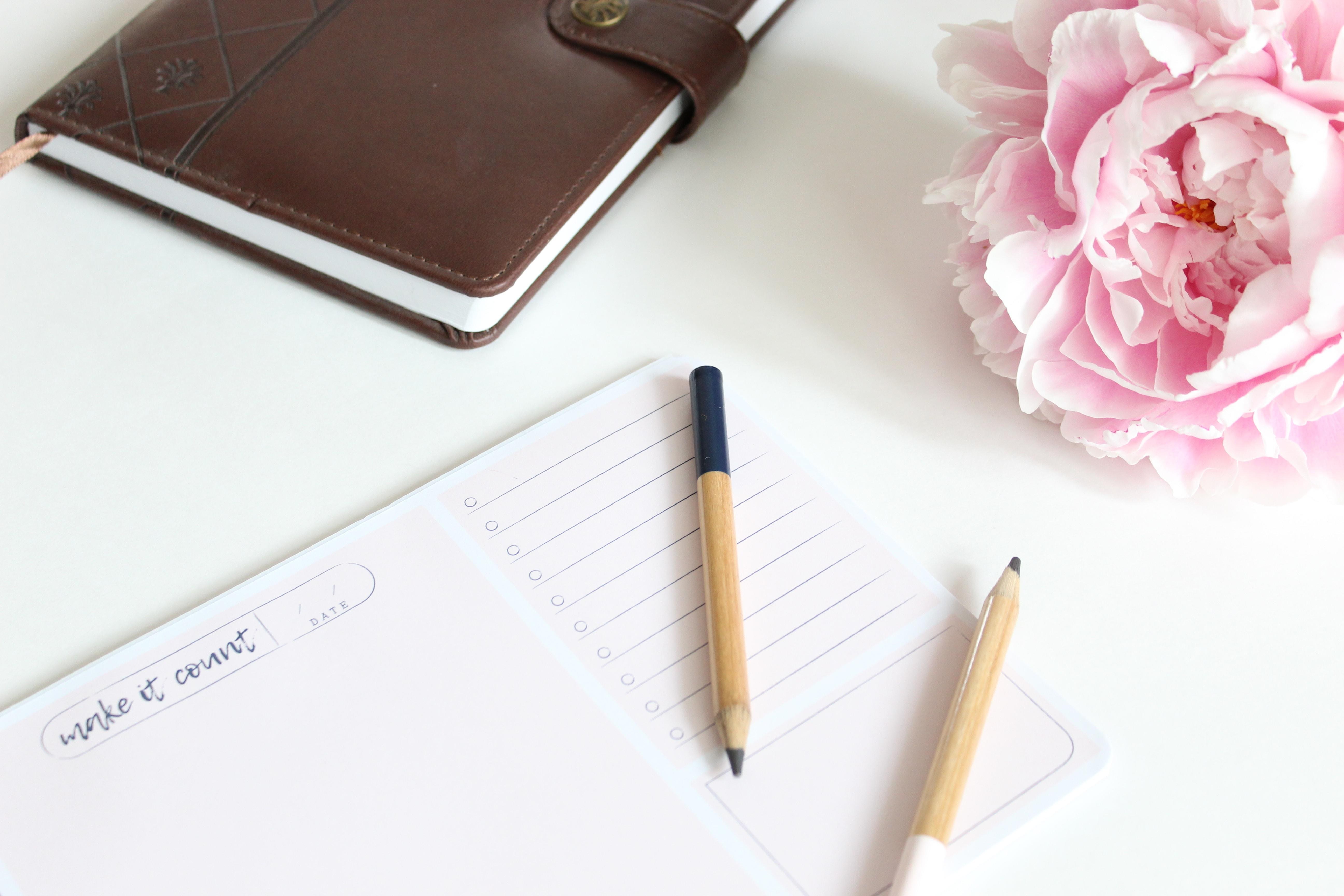 weekly planner, diary, two pencils and flower on desk