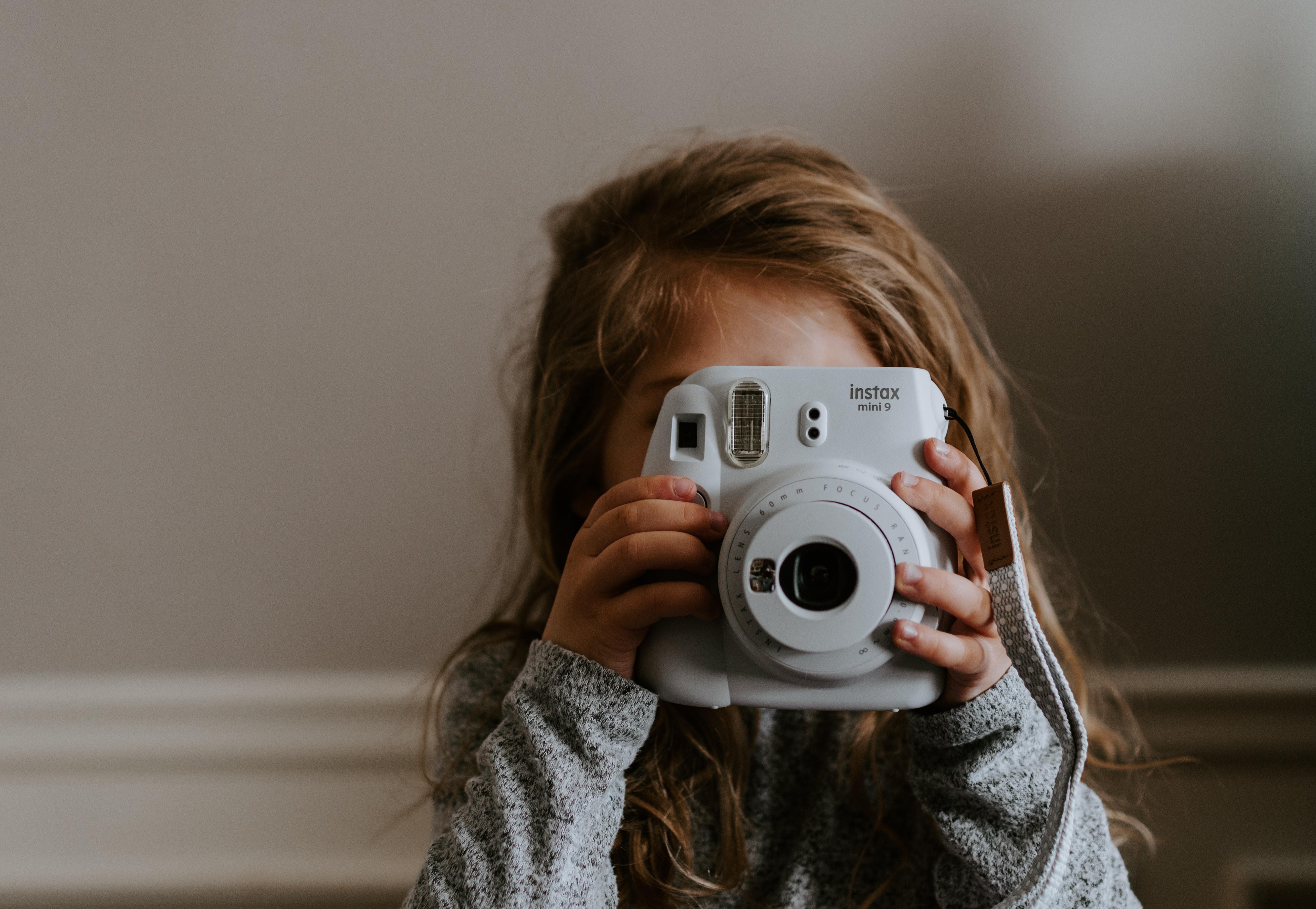 young girl taking photo with instant camera