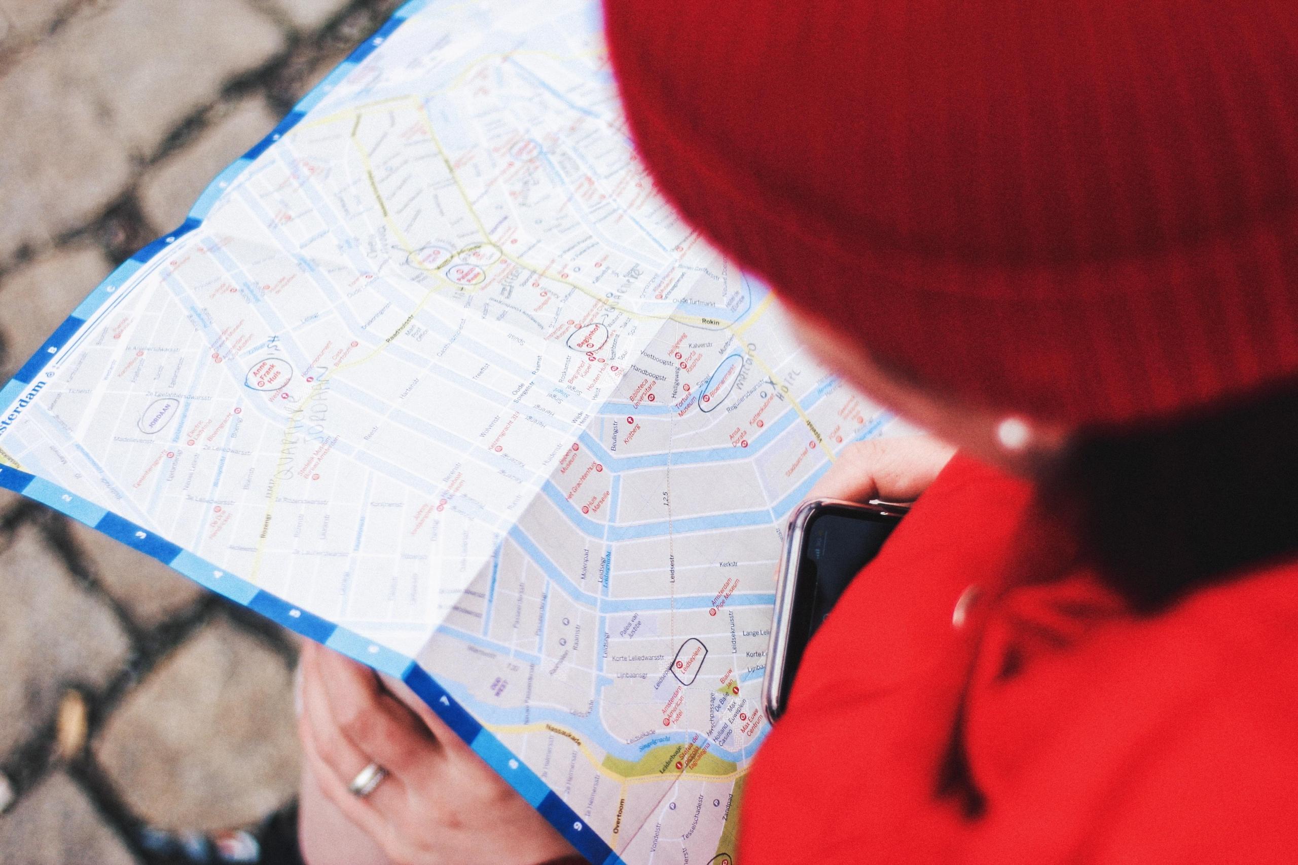 person in red jacket and red hat reading map