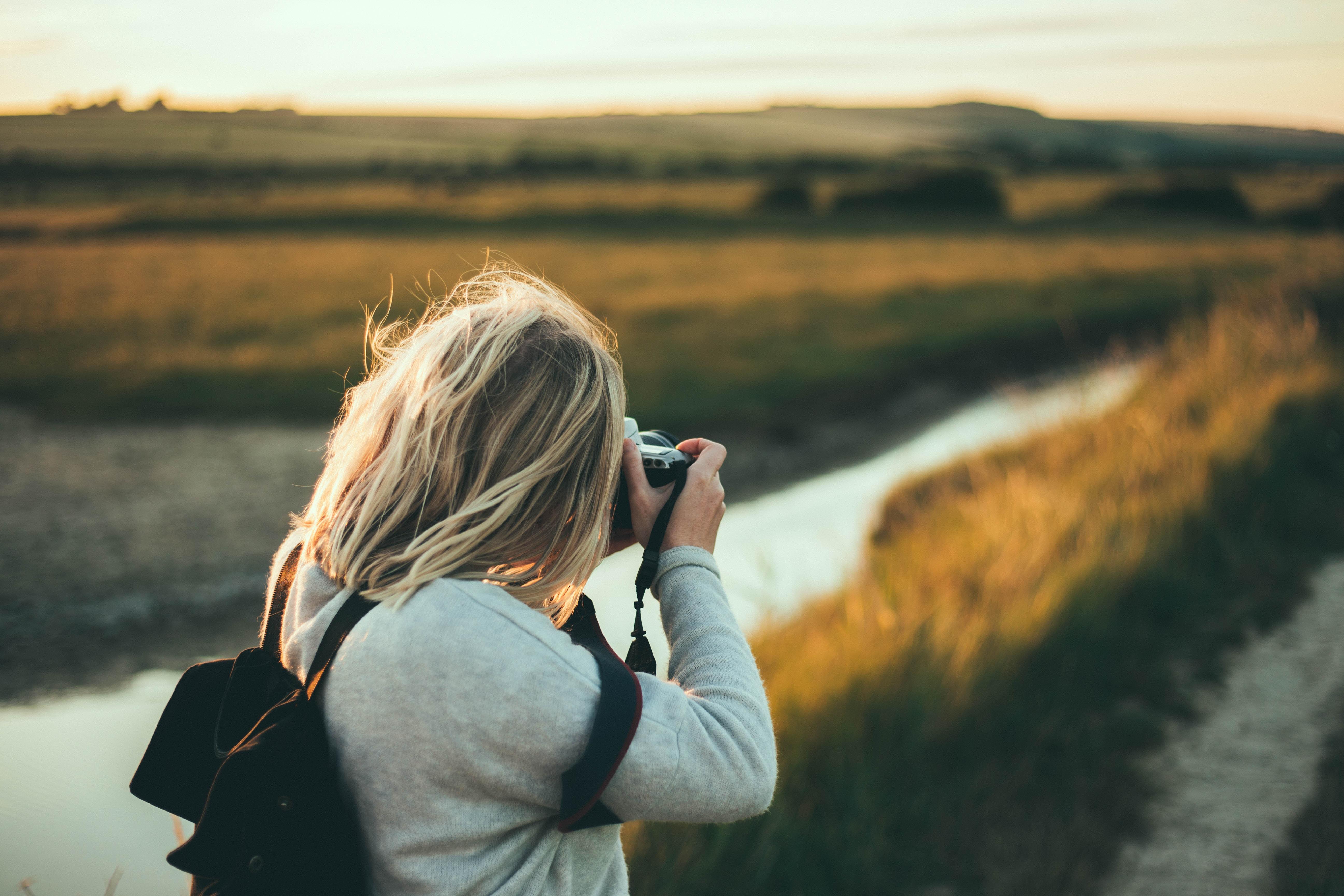 female photographer taking photo in a field at golden hour