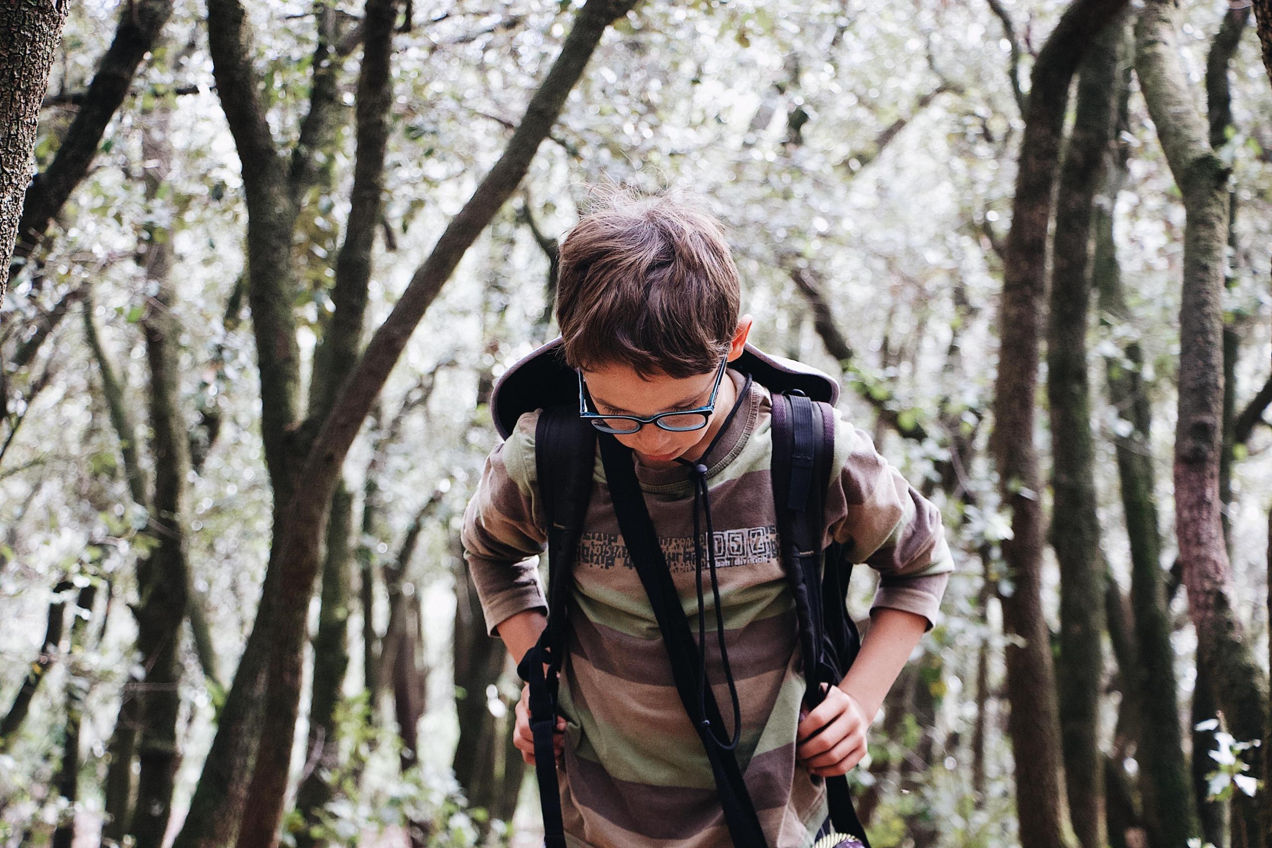 shallow focus school boy walking outside carrying backpack