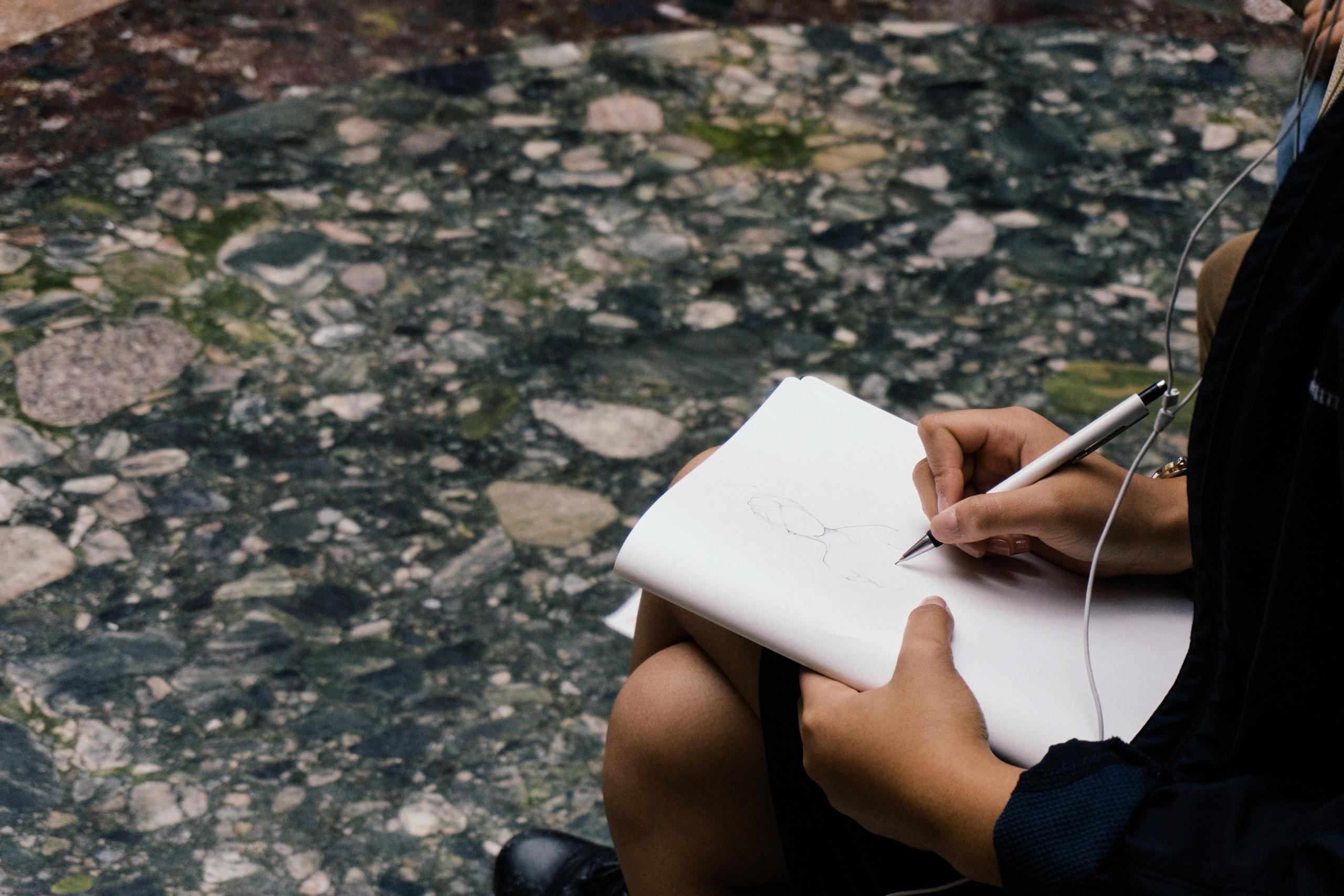 woman listening to headphones whilst sketching