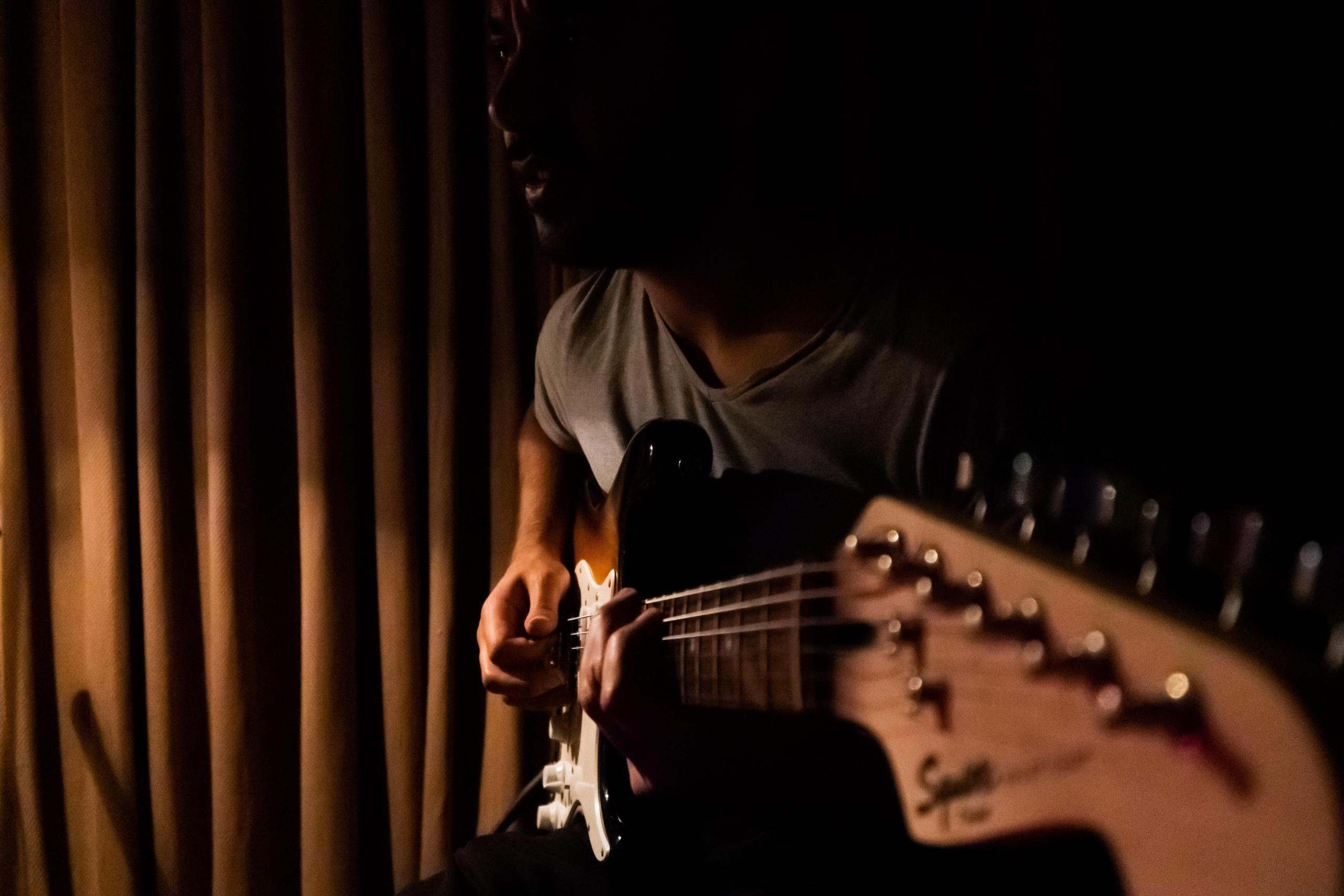 man playing guitar on stage in shadow