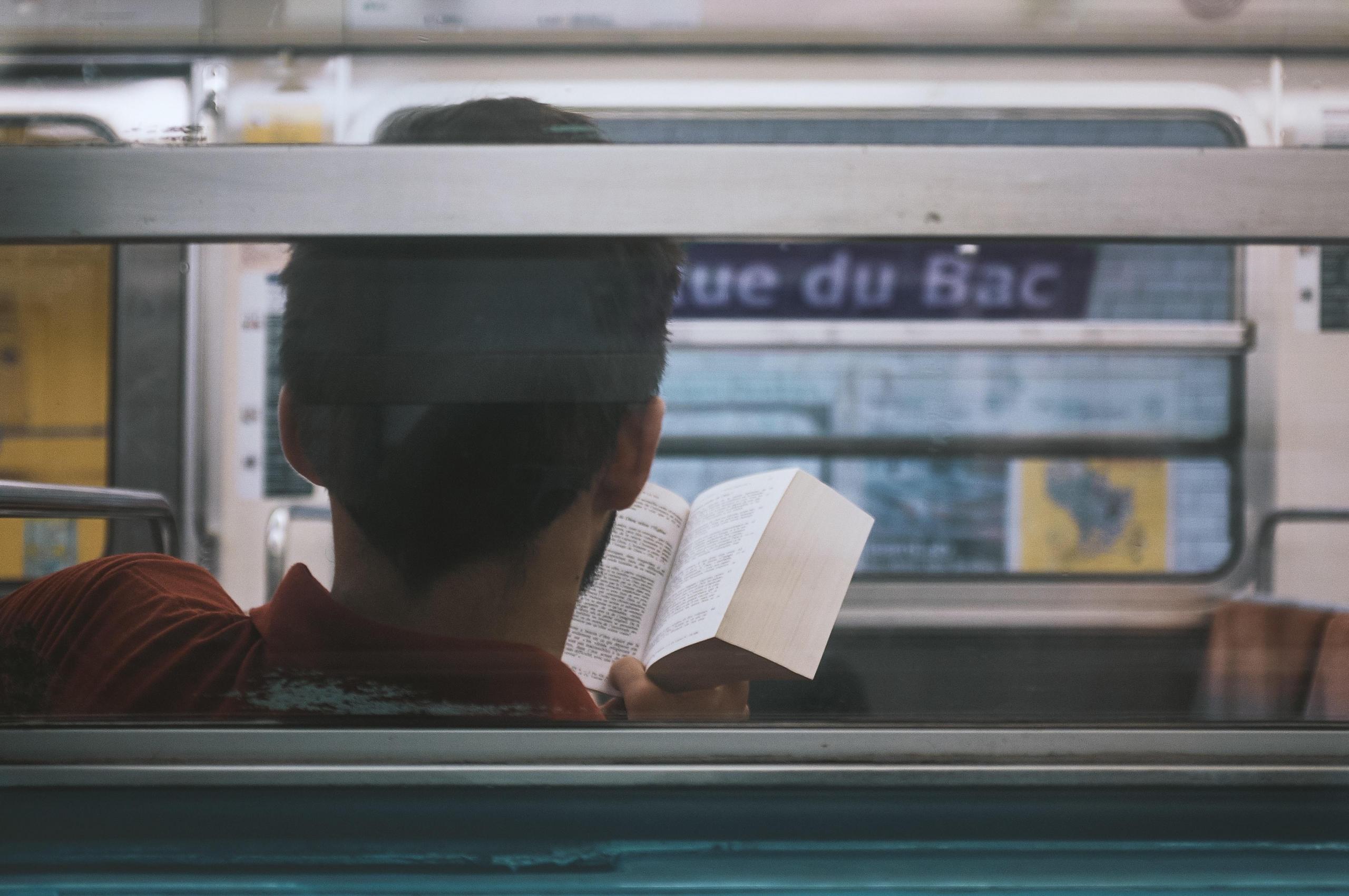 man reading a book in metro train in Paris
