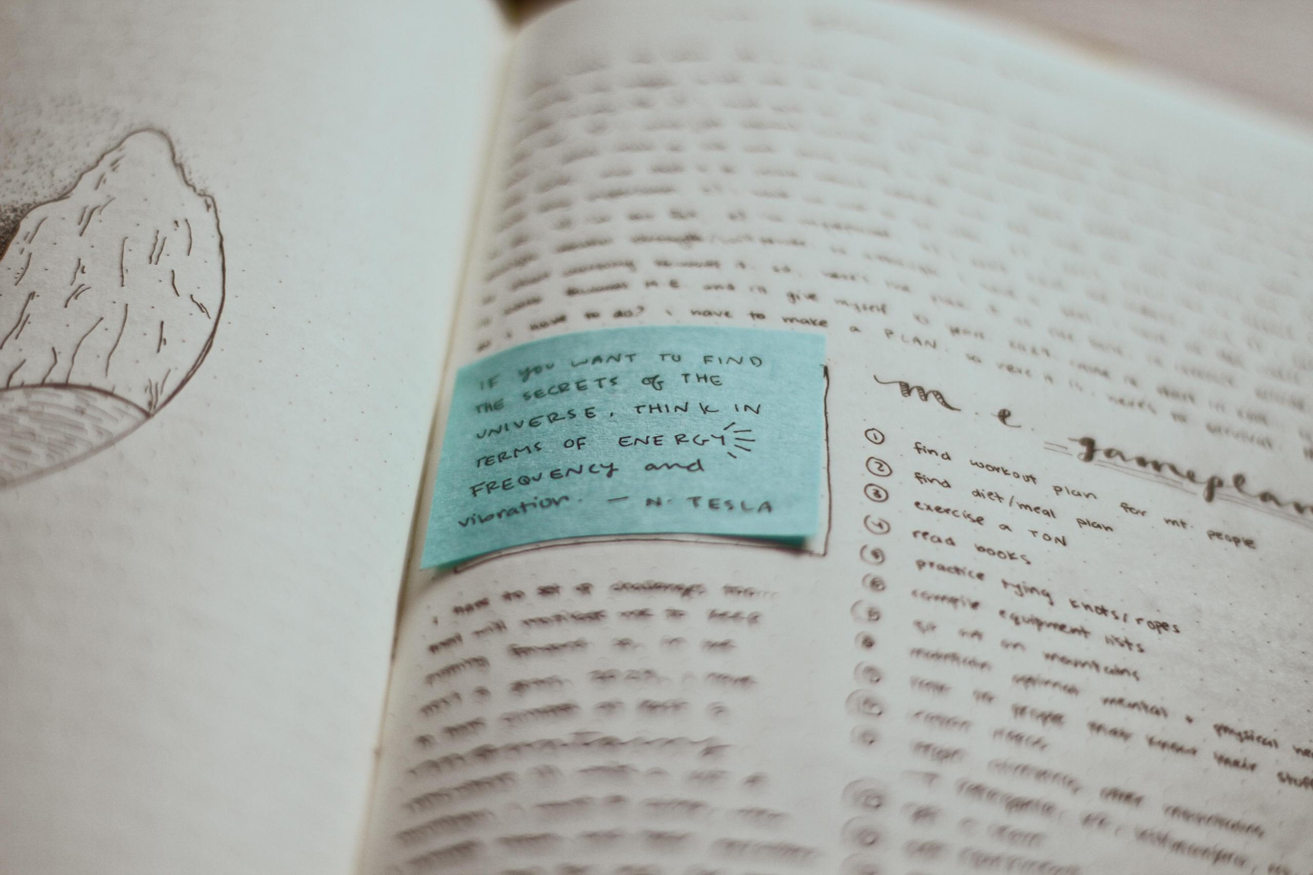 sticky note and open book with handwritten sentences