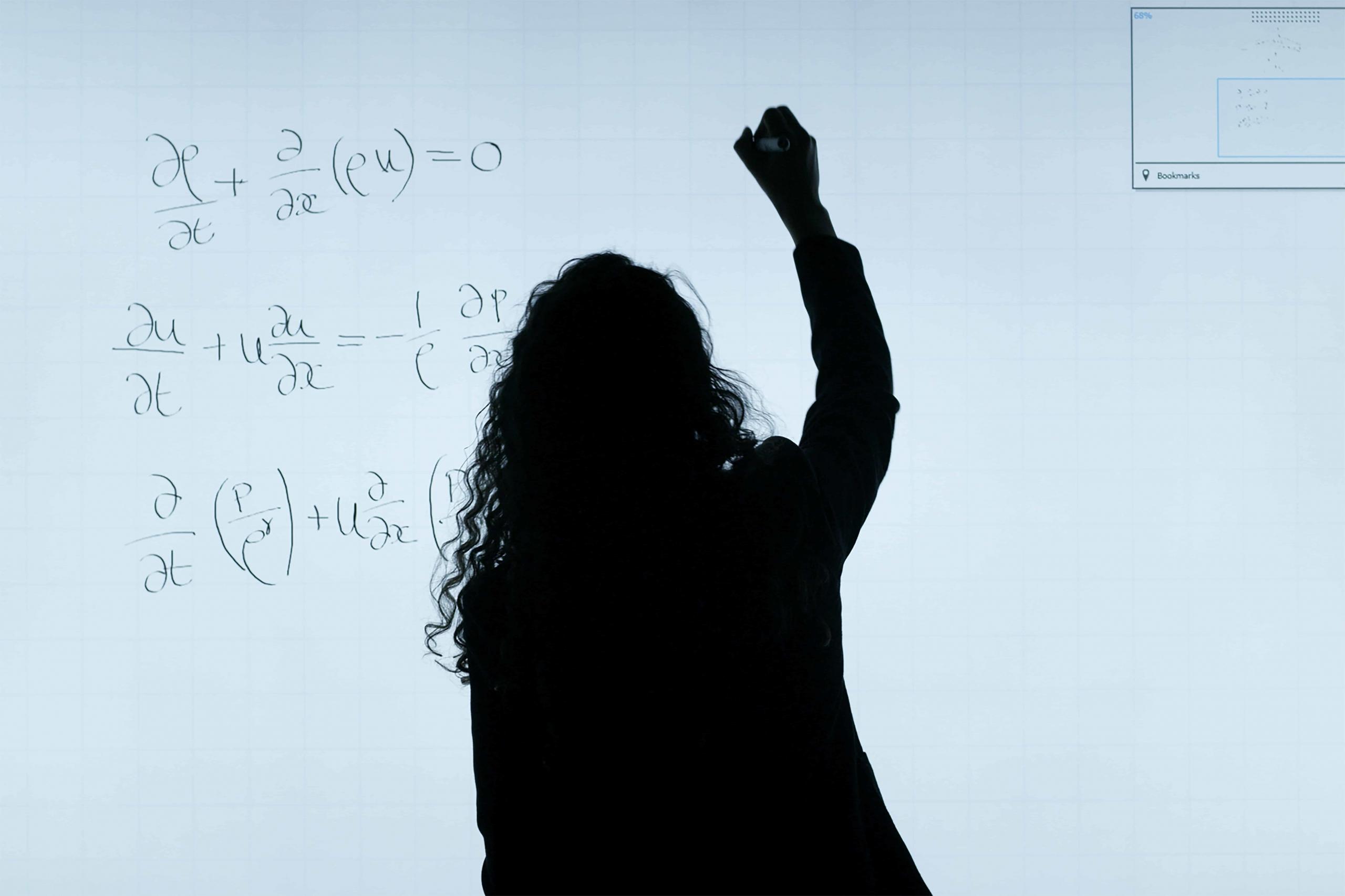 woman solving mathematical formula on whiteboard