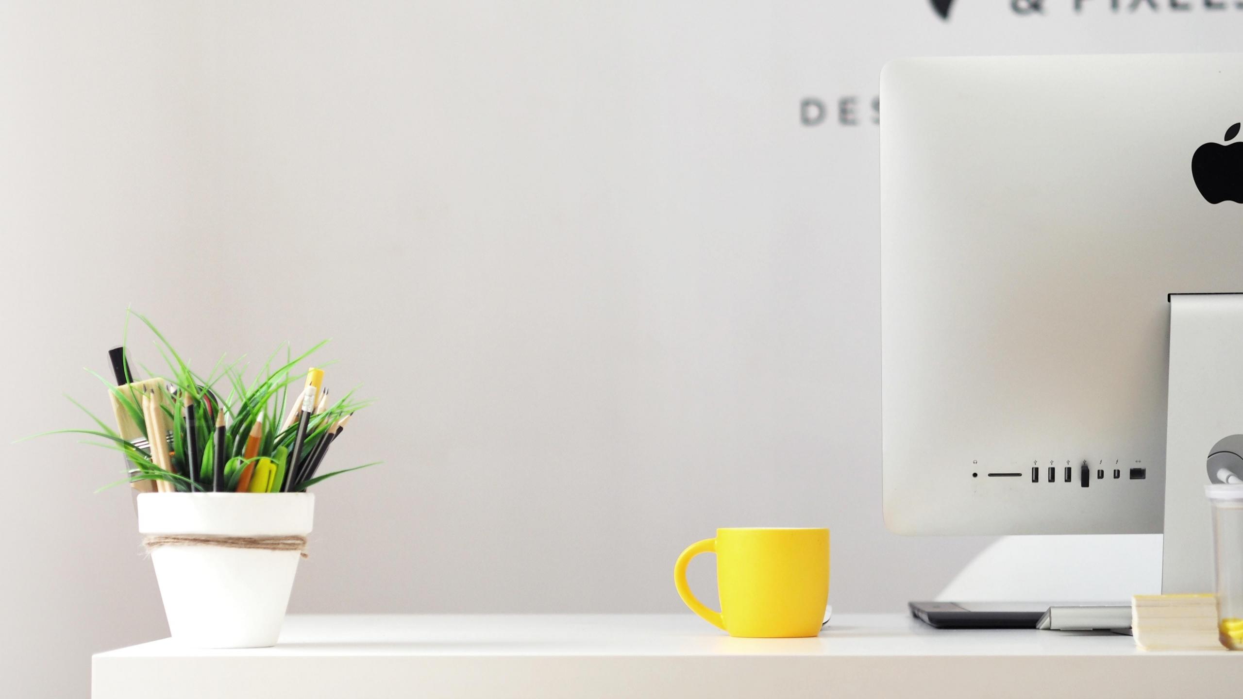 computer on desk with stationery and mug