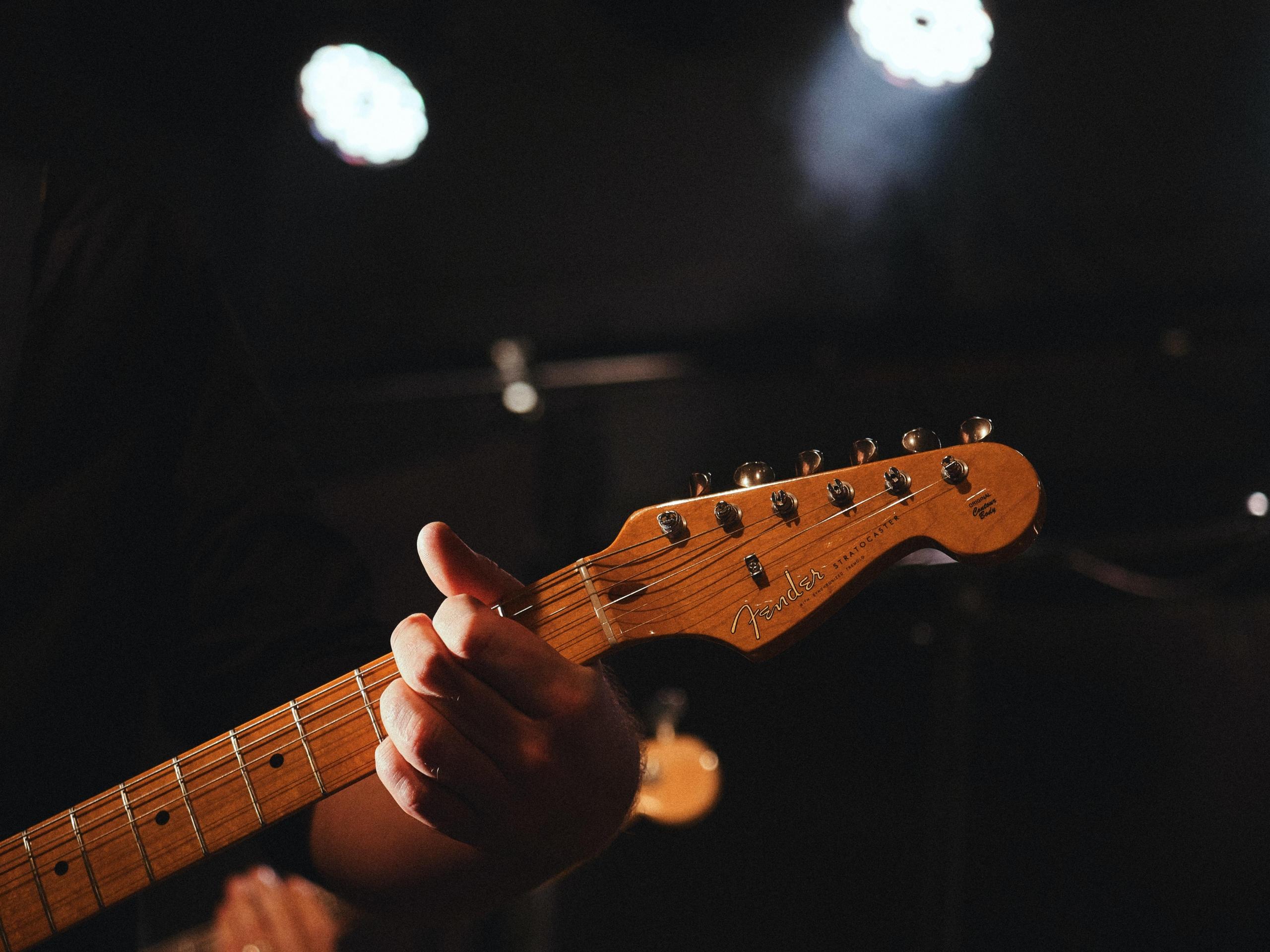 person playing acoustic guitar one-handed